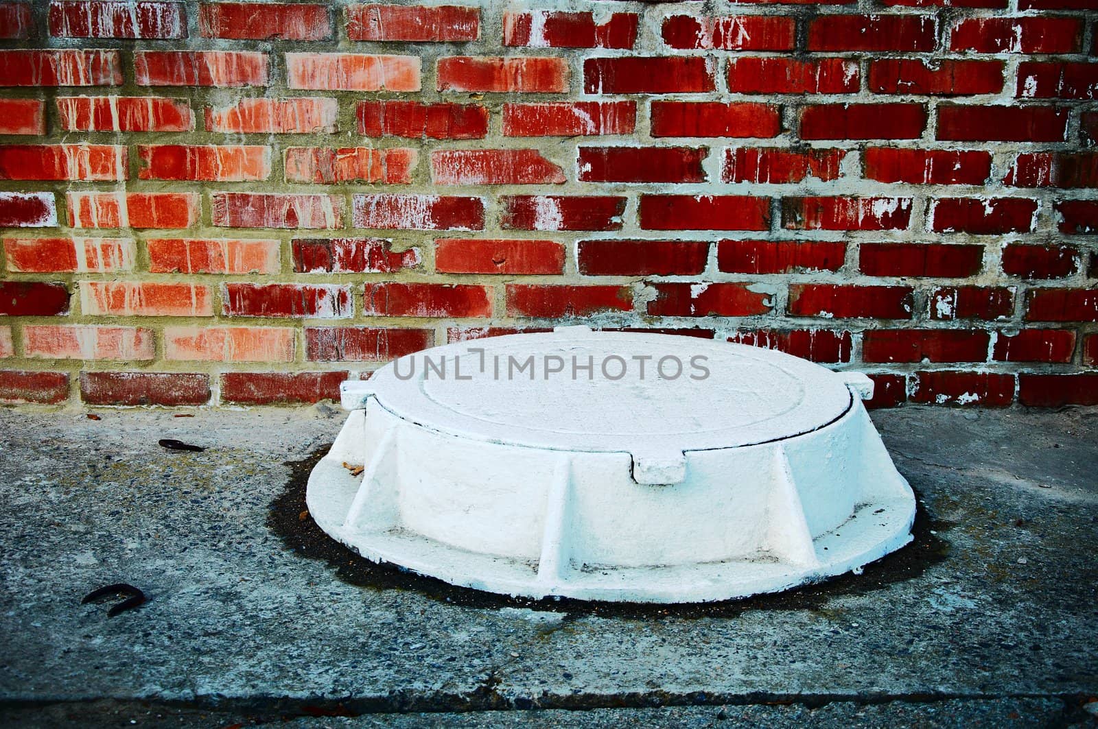 The white manhole against a brick wall in style grunge