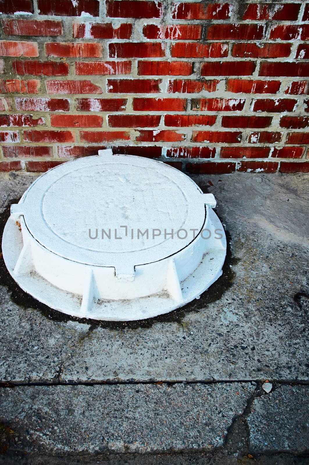 The white manhole against a brick wall in style grunge