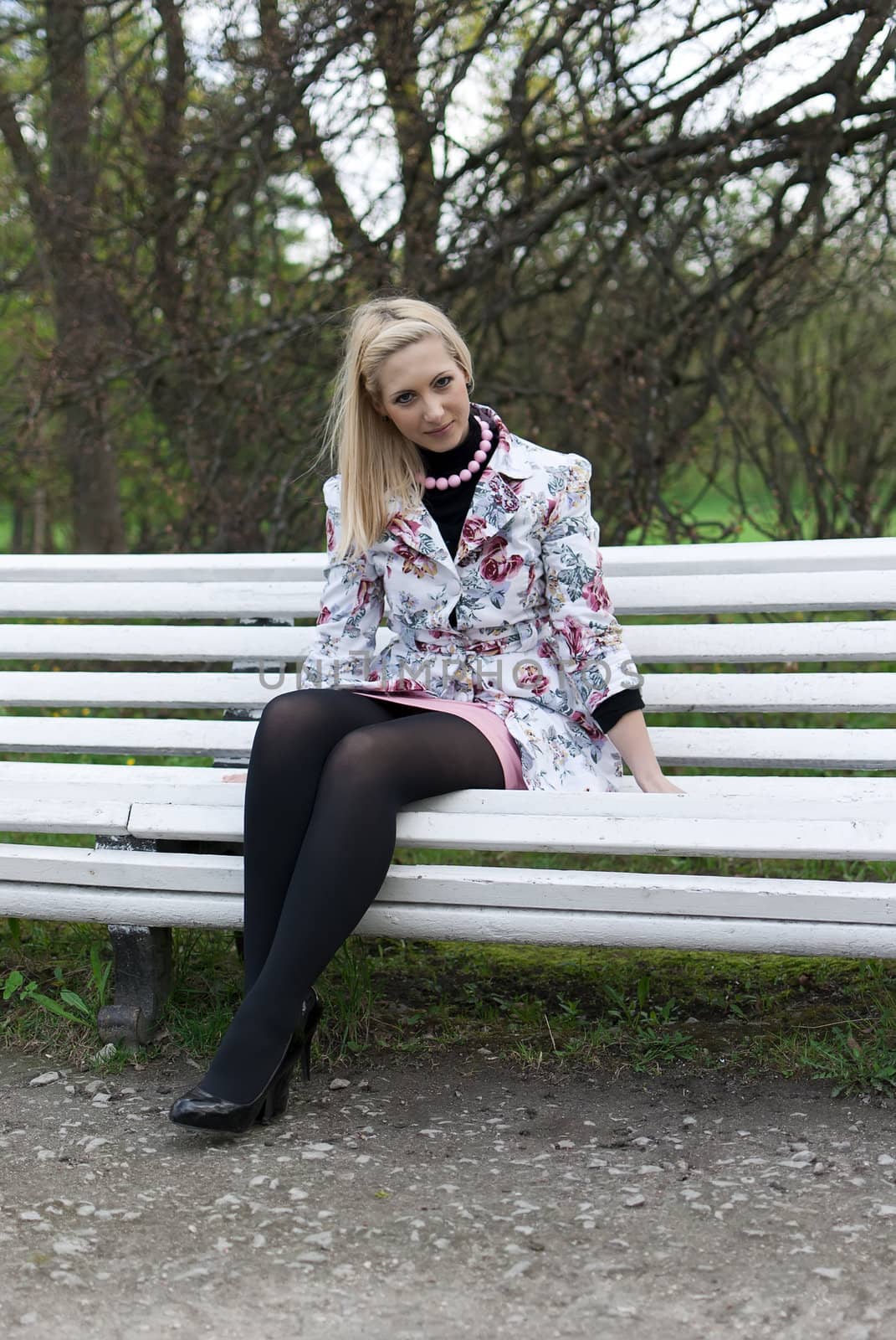 blonde girl sitting on a park bench and smiling