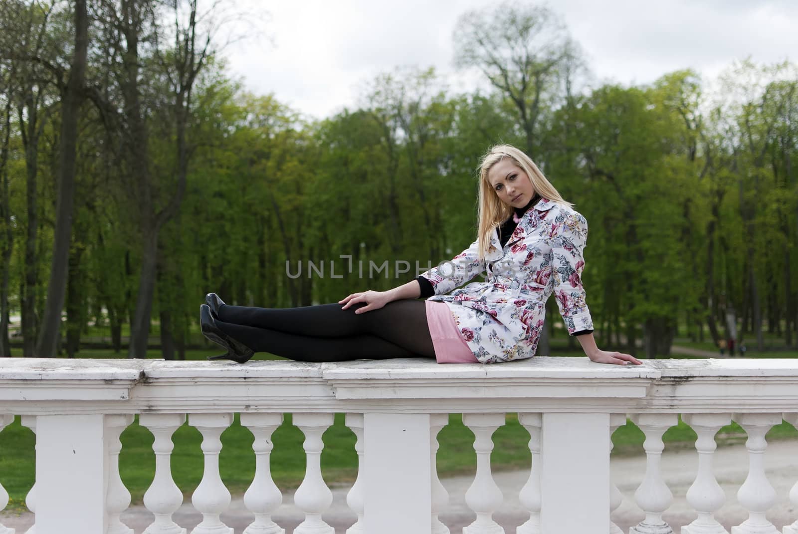 blonde girl sitting on the railing of the old palace