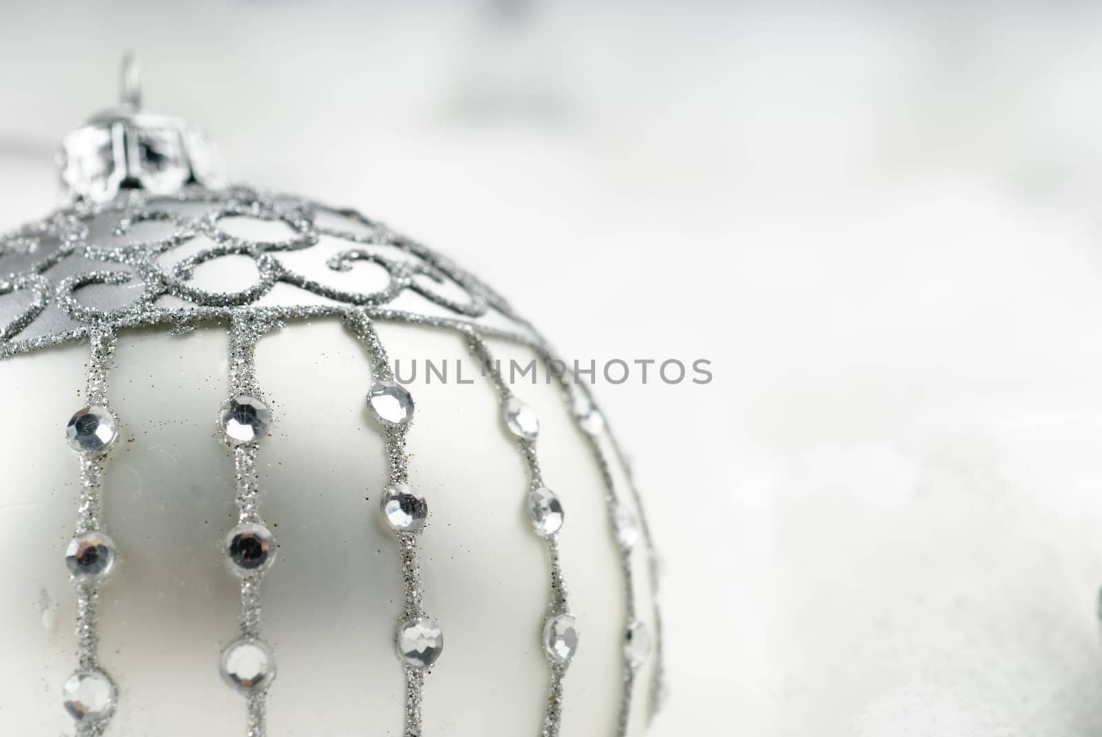 Silver christmas bauble with crystals surrounded by fluffy snow