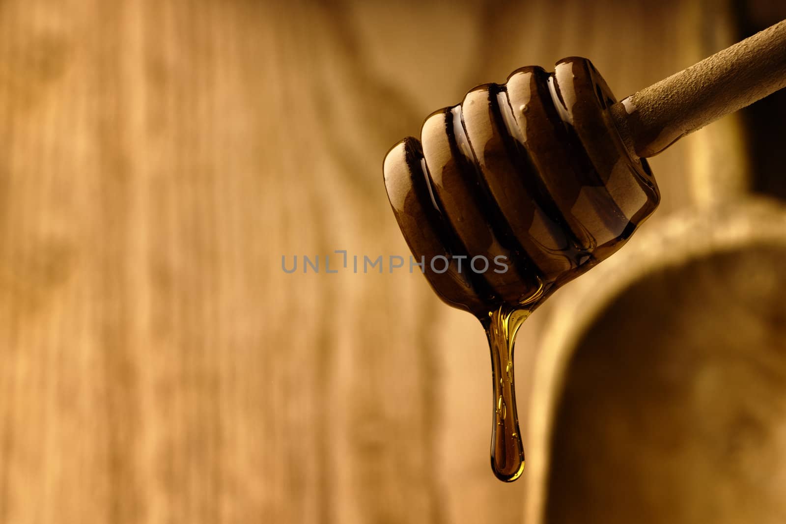 Wooden dipper with golden honey surrounded by wood