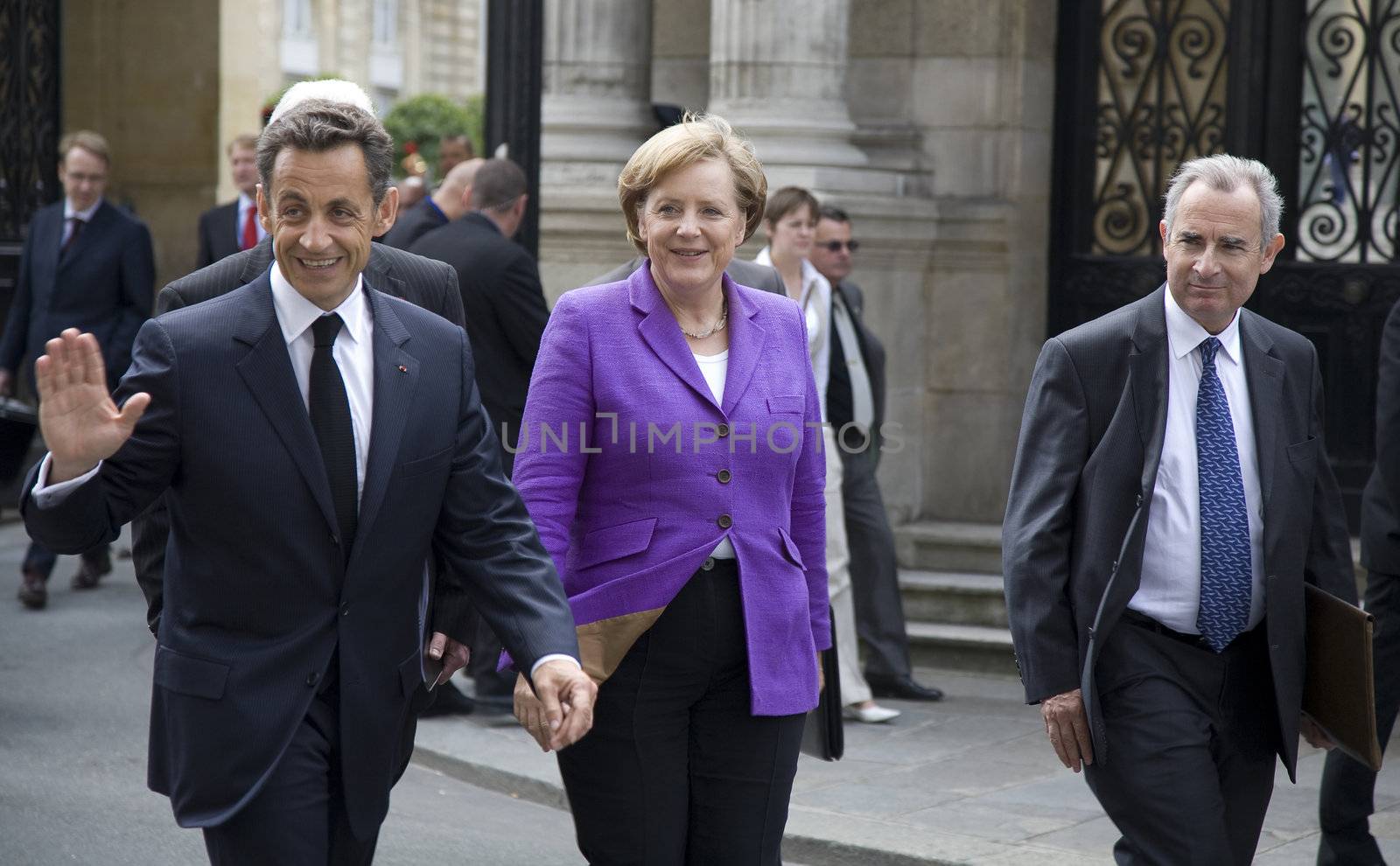 PARIS, FRANCE - JUNE 11 - 2009: French president Nicolas Sarkozy (waving) and German chancellor Angela Merkel (C) outside the Elysee Palace on their way to lunch.