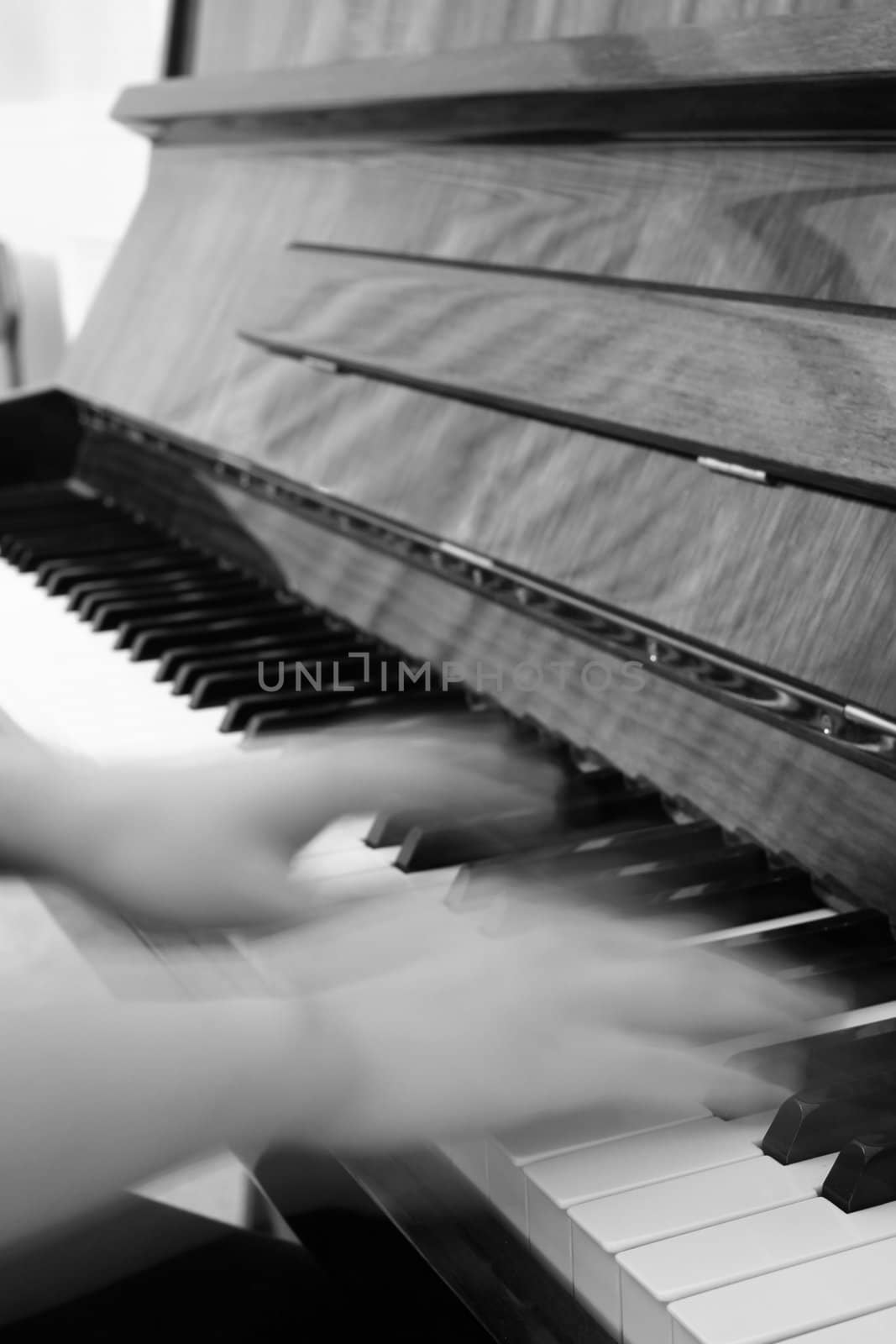 A person playing the piano with motion-blurred hands to mimic fast movement.