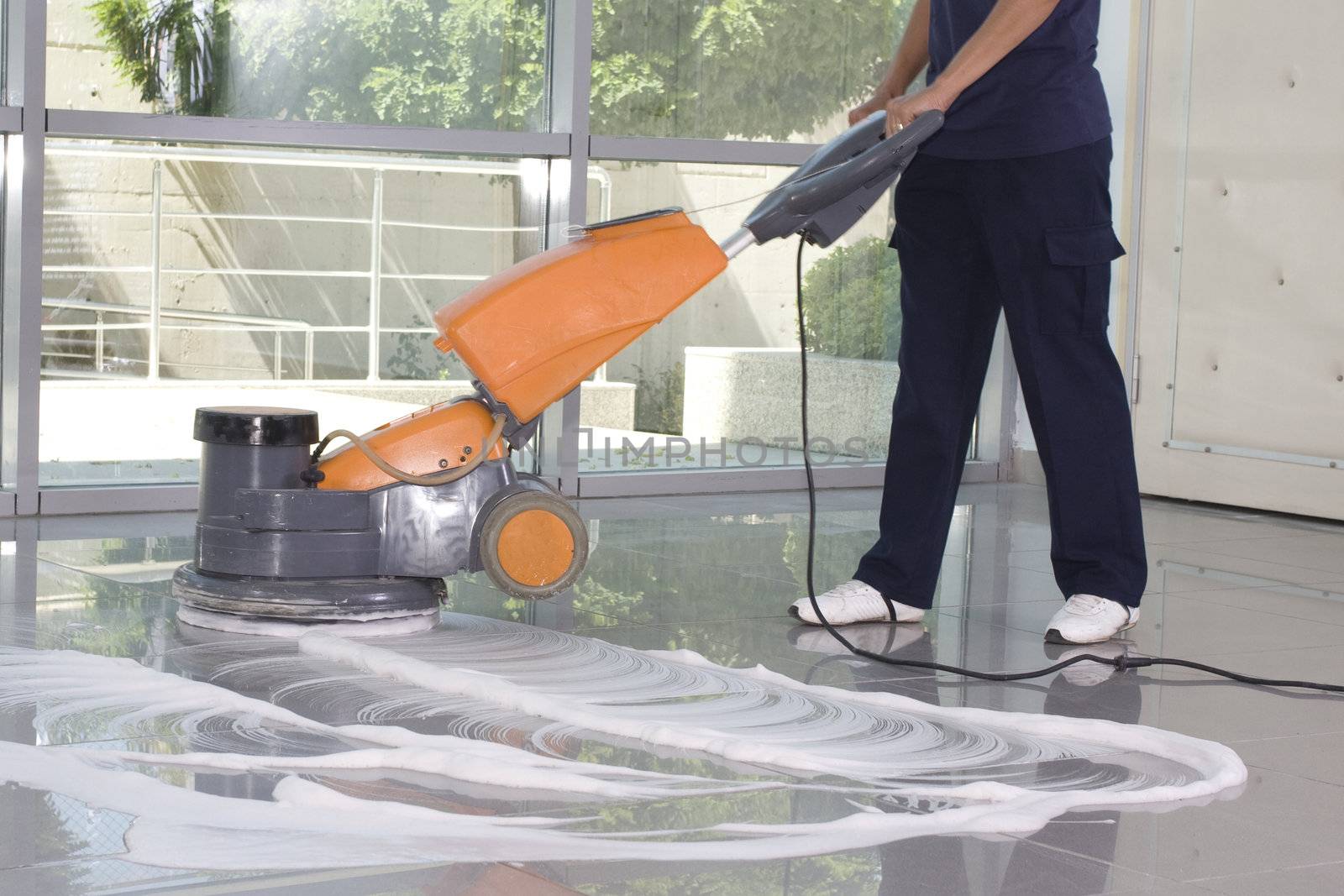 A worker is cleaning the floor with equipment