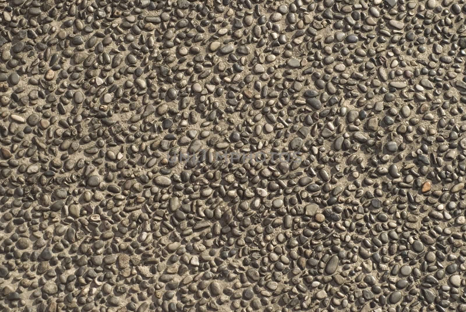 Close up of detail of concrete paving with tiny pebbles in sidewalk. 