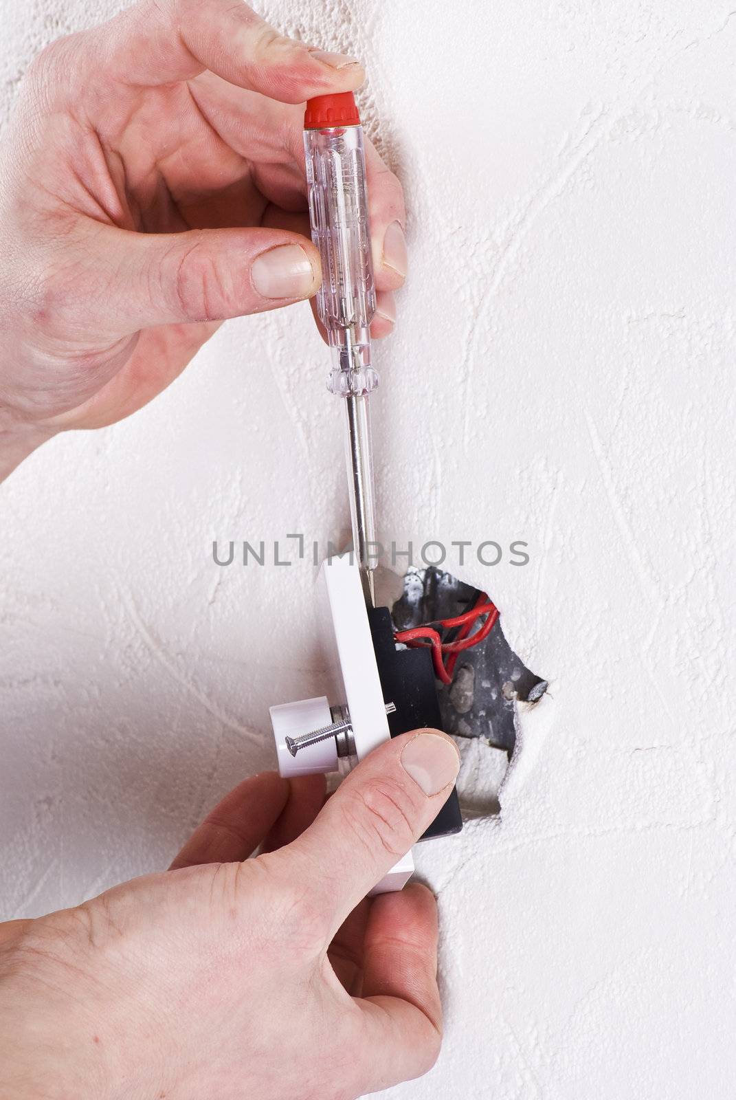 Hands of electrician fitting new light switch