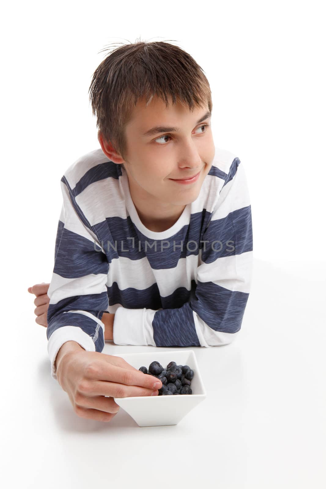 Boy with a bowl of berries.  He is looking sideways, suitable for message.  White background.