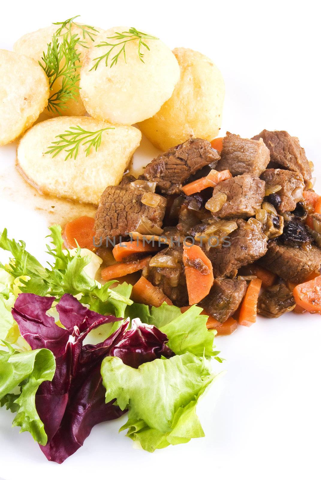 Meal of stewed beef steak with roast potatoes and fresh salad