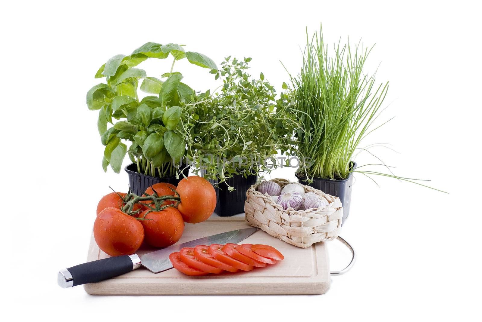 Herbs with chopping board of tomato and garlic by caldix