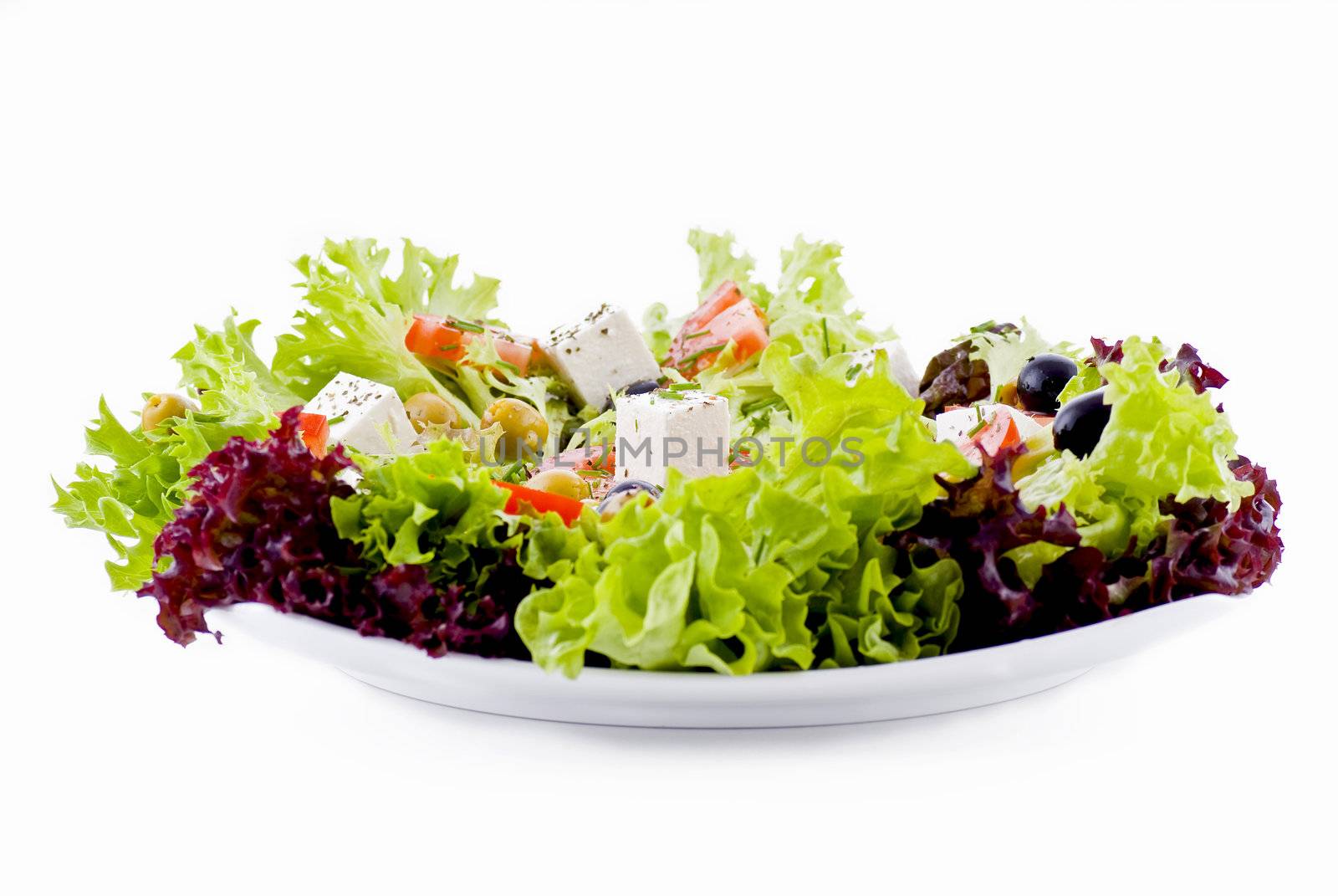 Plate of fresh vegetables - salad, olives, tomato, feta and herbs