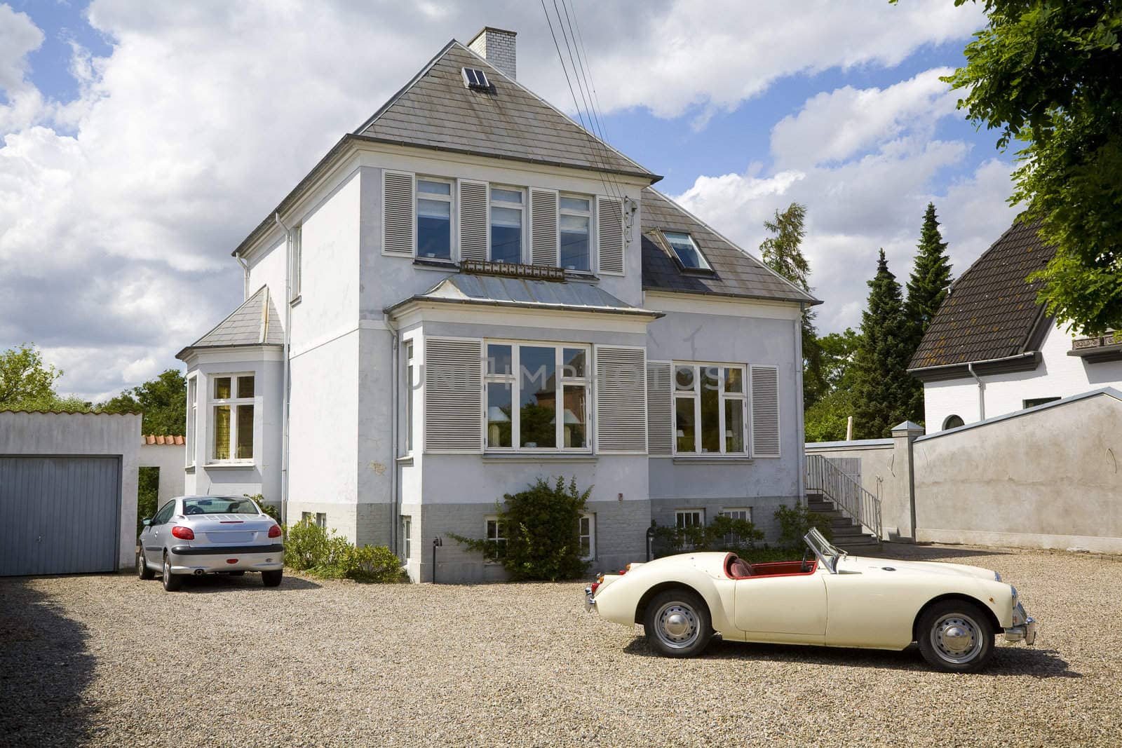 Old Danish villa with two cars in the driveway.