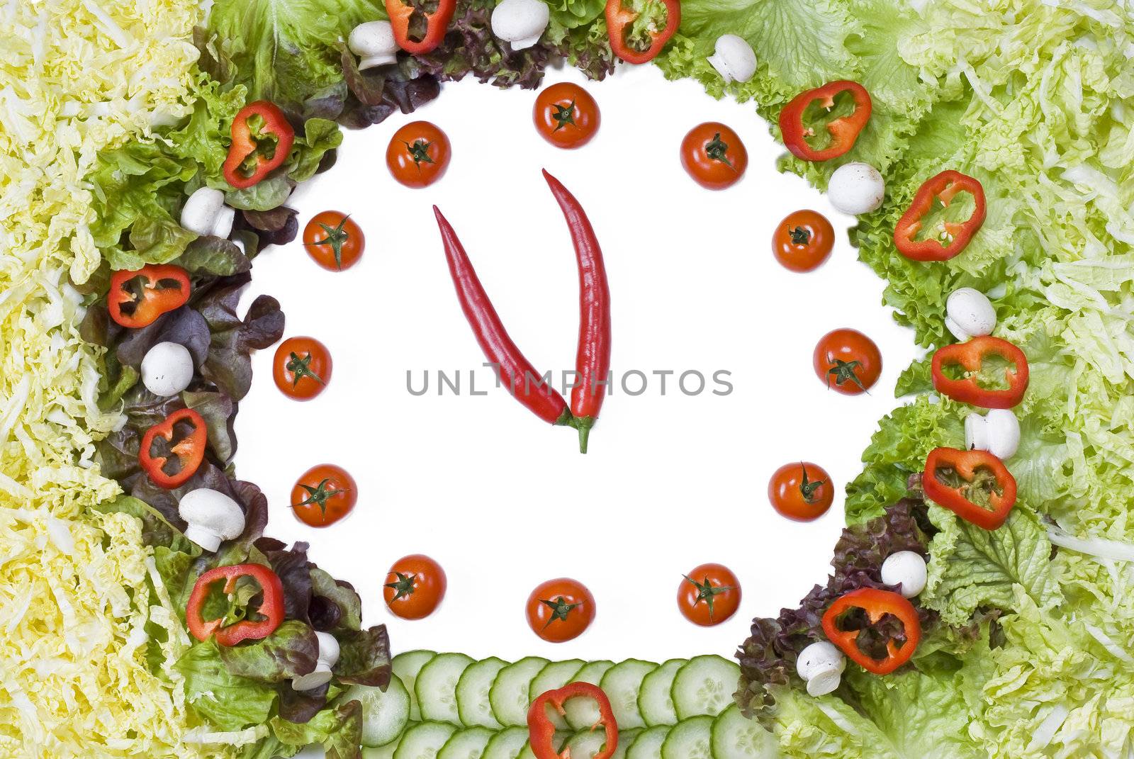 Vegetable clock created on white background from fresh vegetables