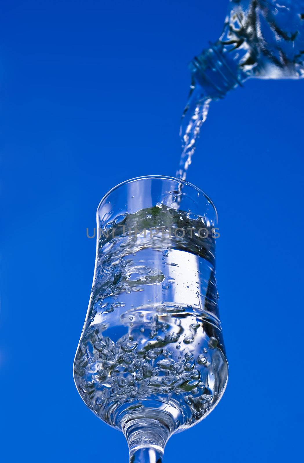 Pouring glass of water on the blue sky background