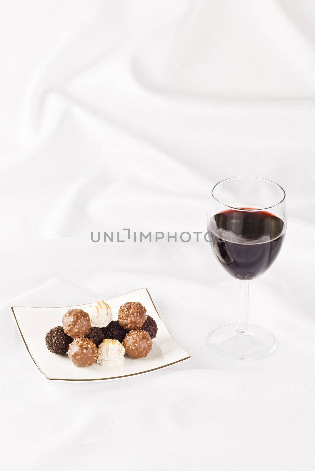 Red wine and plate of chocolate on the table cloth