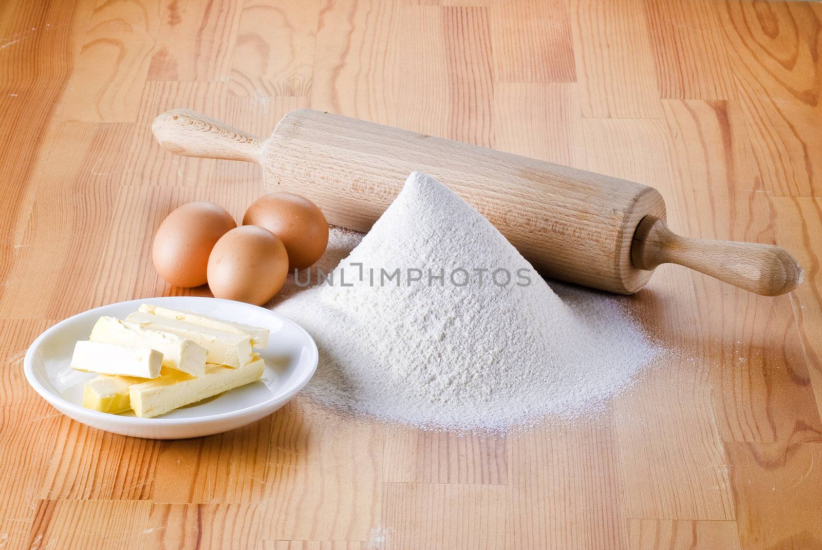 Flour with eggs, rolling pin and butter by caldix