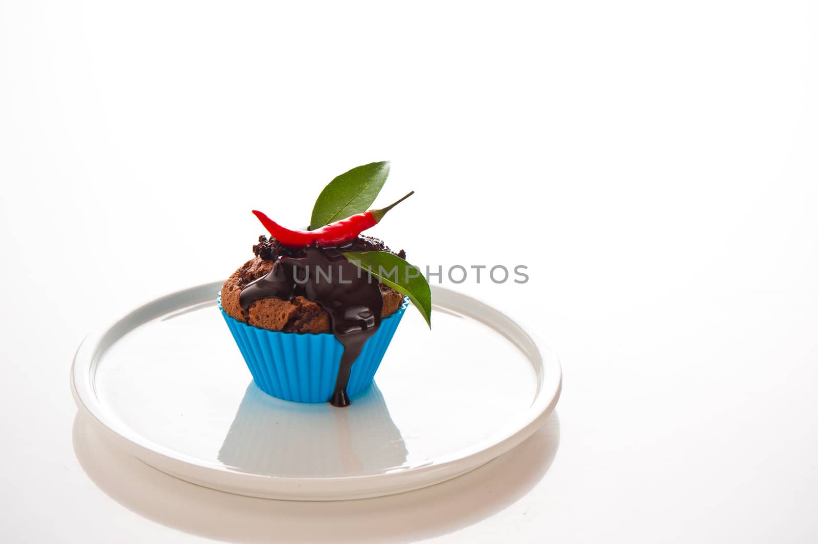 Hot chocolate cupcake with liquid chocolate and a red chili as a studio shooting