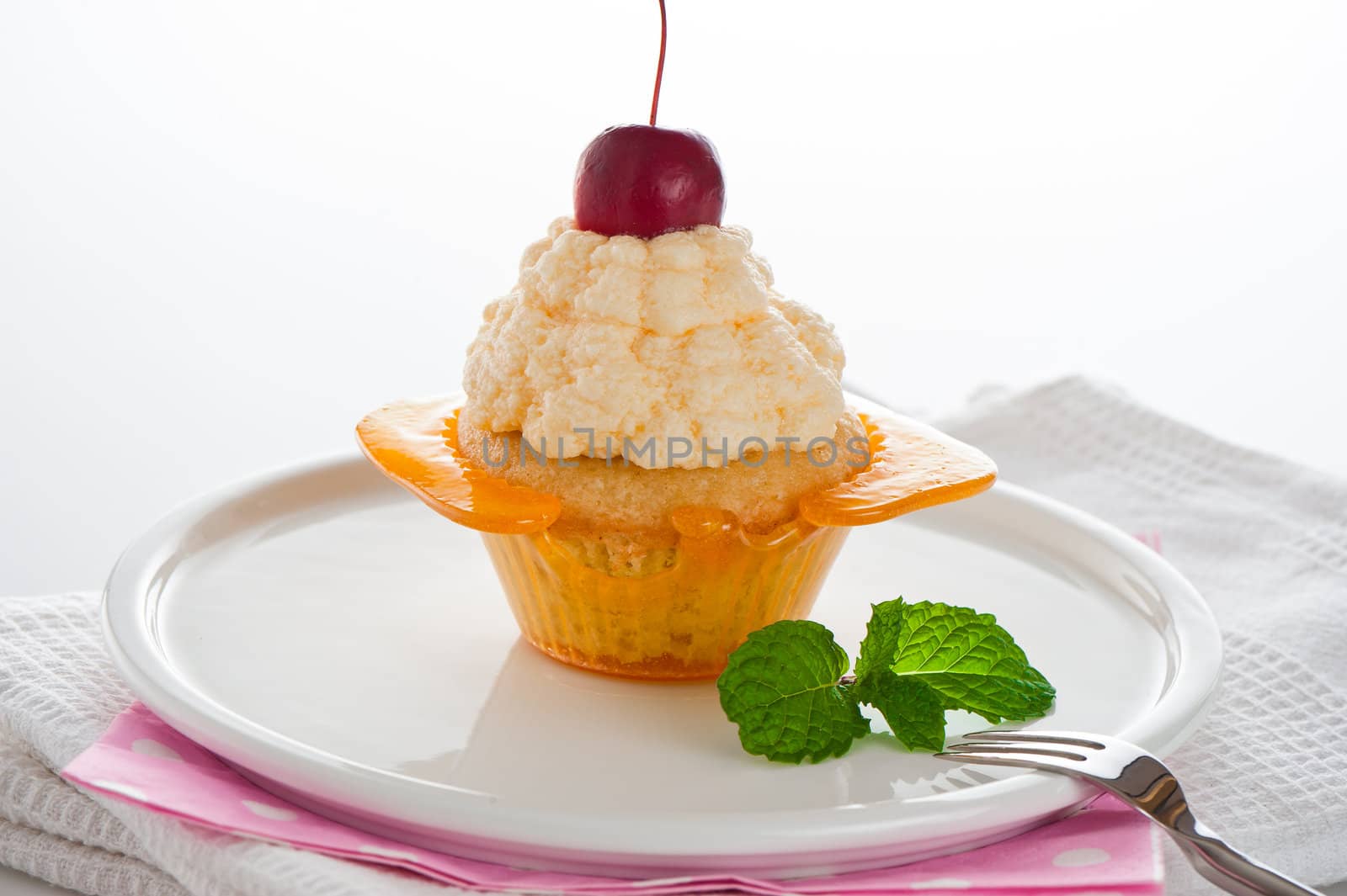 A cupcake in a cup of caramel with vanilla cream on white background