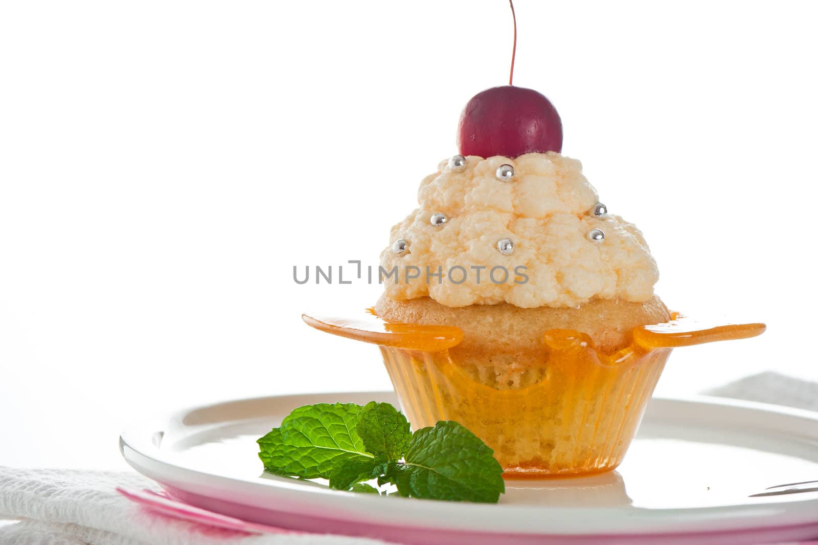 A cupcake in a cup of caramel with vanilla cream on white background