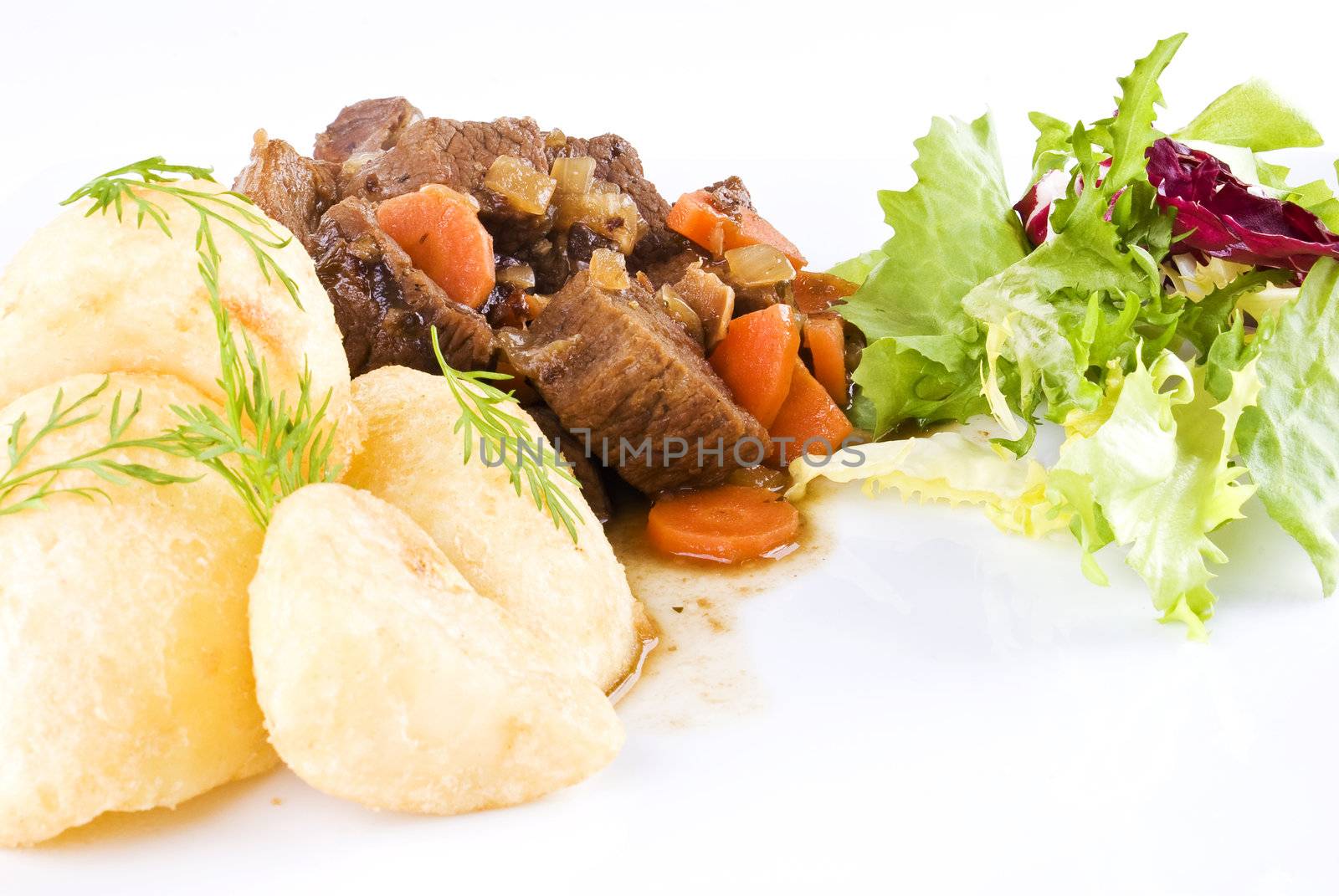 Meal of stewed beef steak with roast potatoes and fresh salad