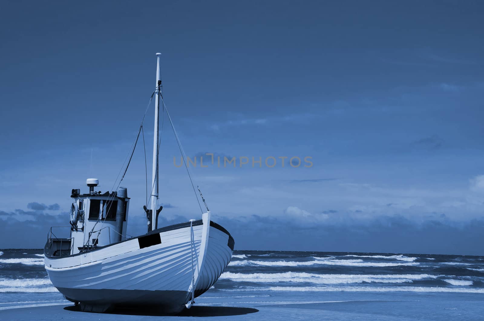 A fishingboat is lying on a sandy beach