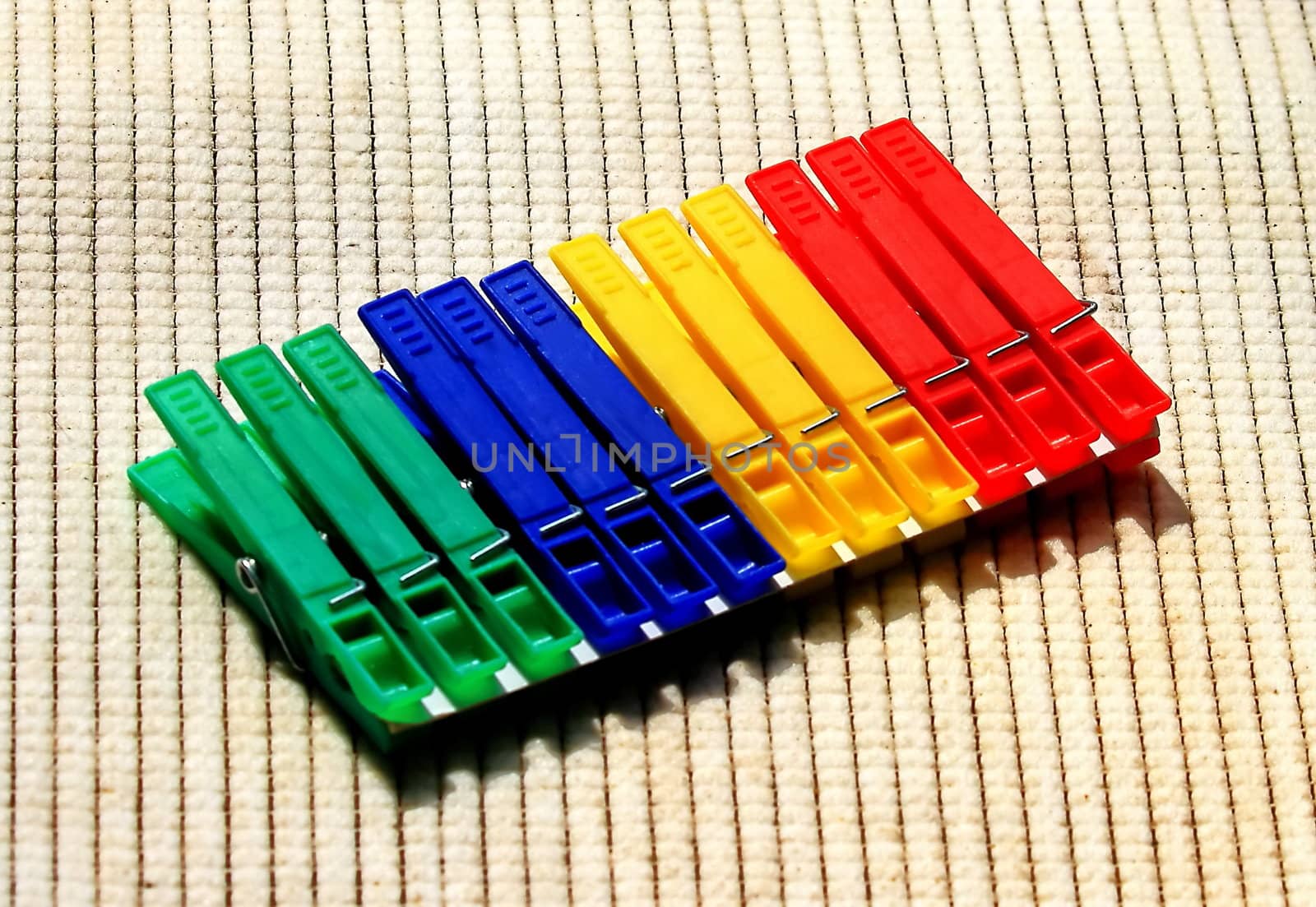 twelve pegs for clothes of different colors on a beige background.