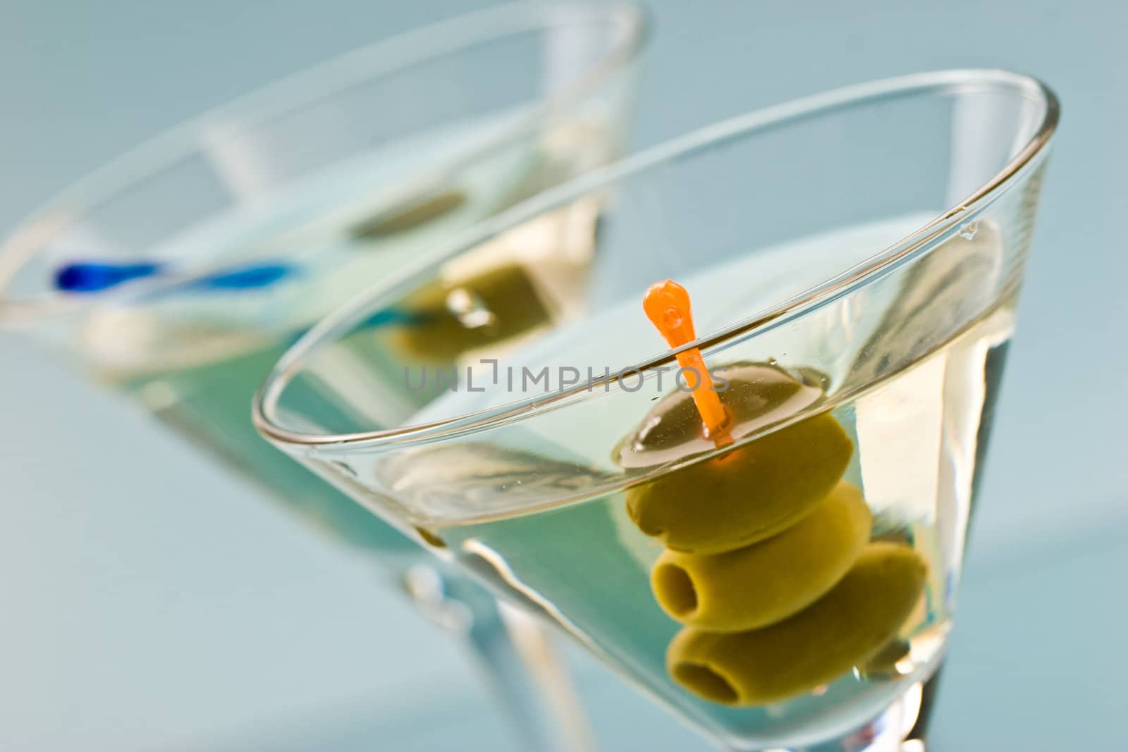 two bocal of martini with olive over blue