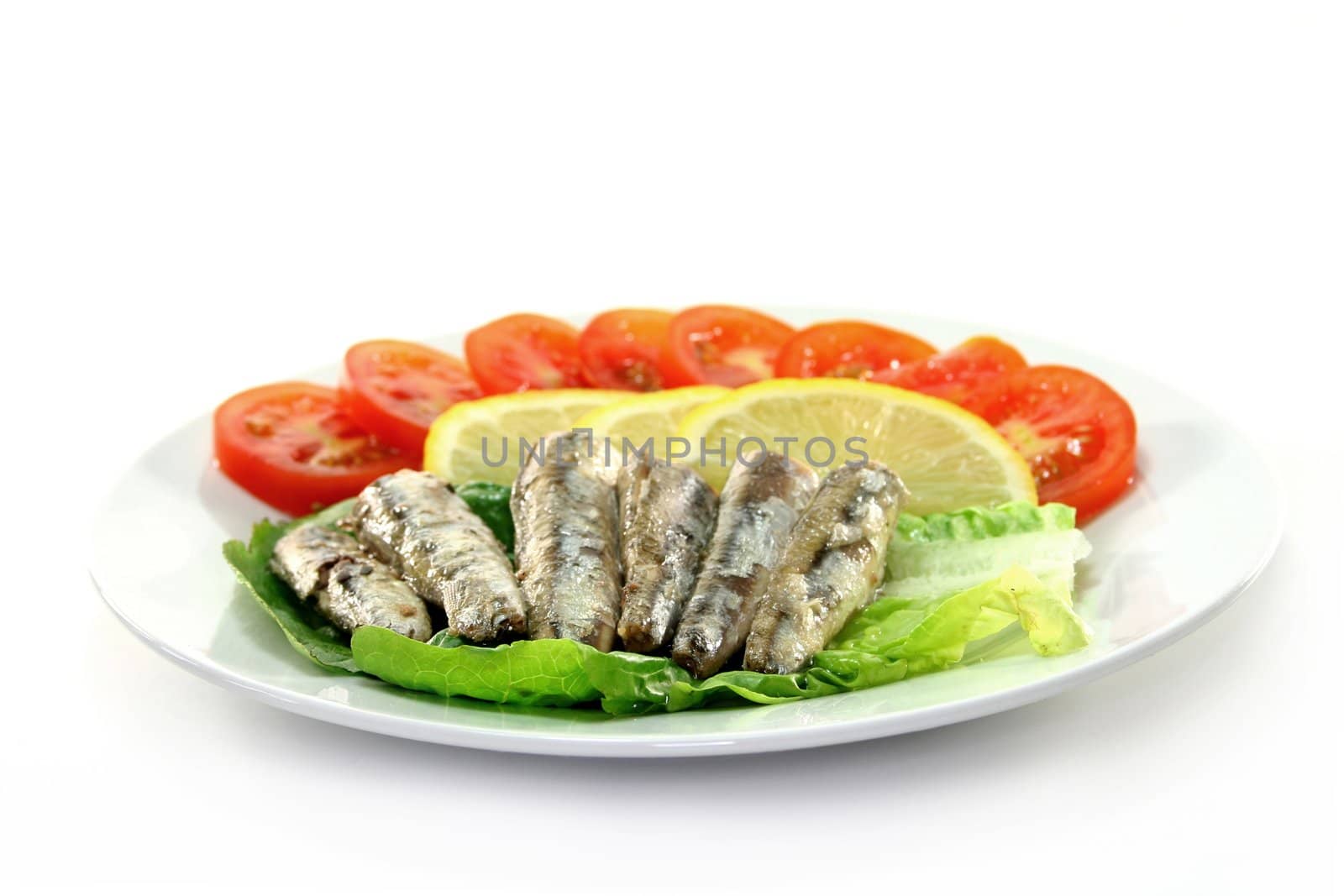 Anchovies with tomato and lemon on a plate