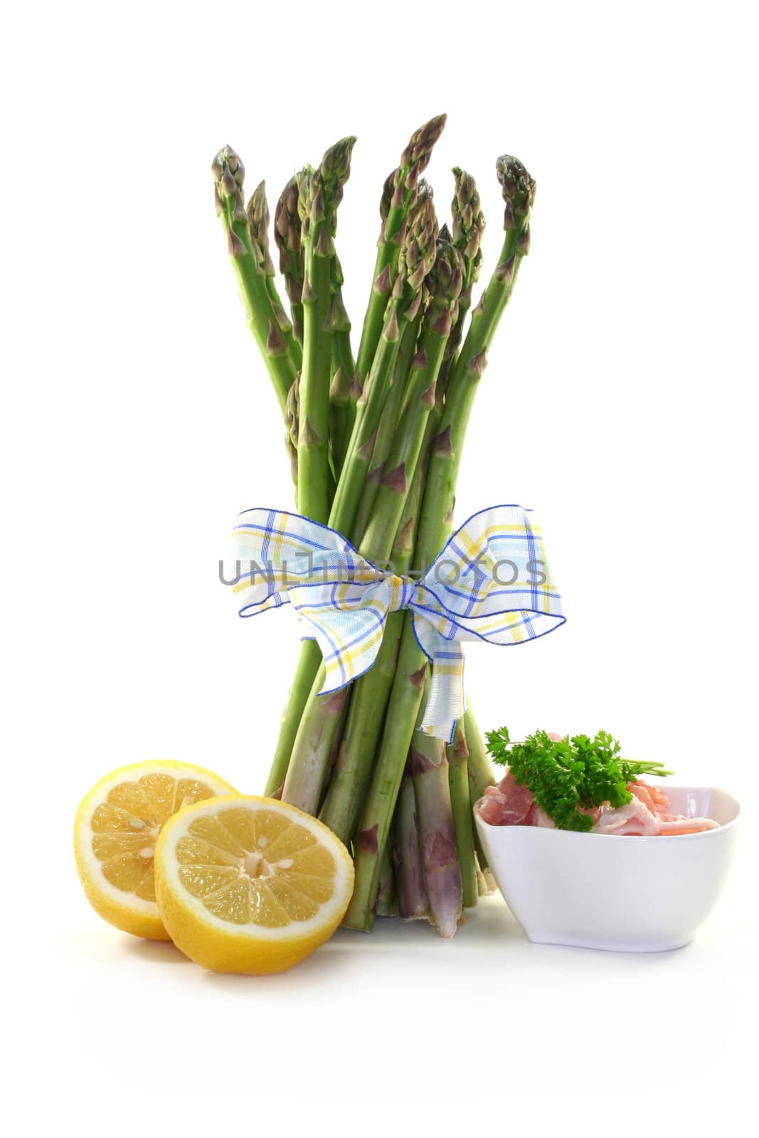 a bundle of green asparagus with lemon and ham