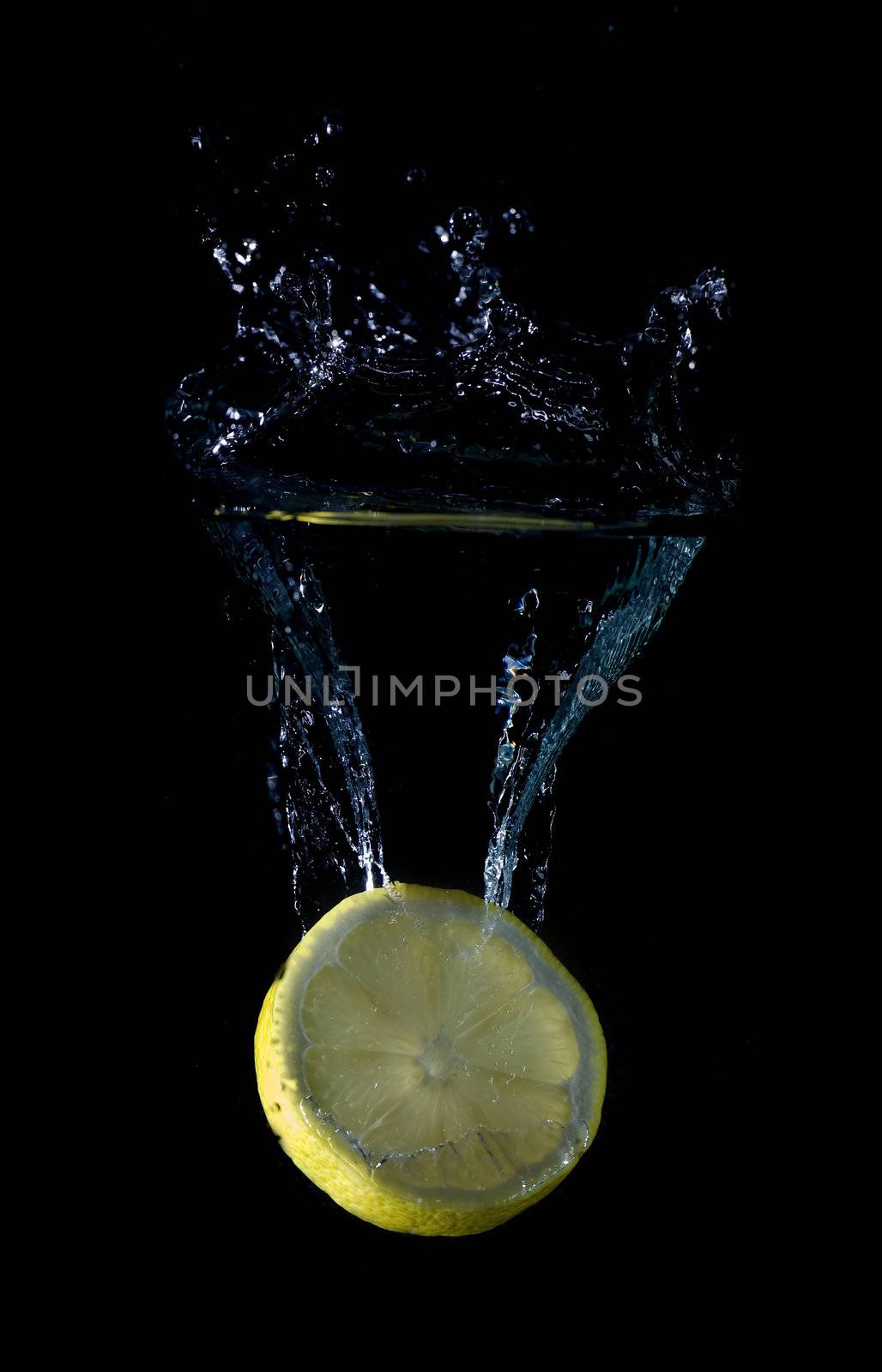 Lemon splashing on a water surface with a black background.