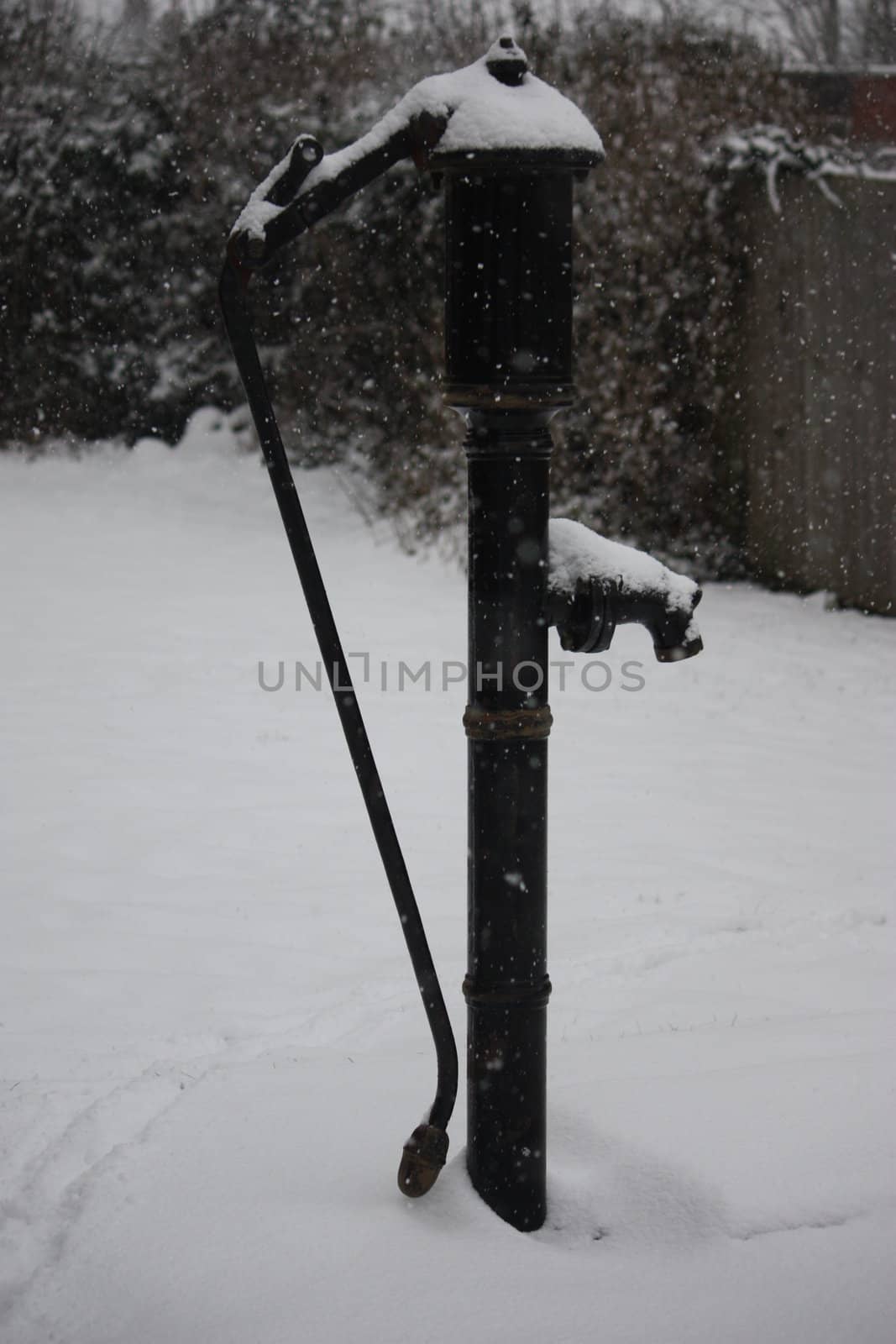 A snow covered old fashioned water pump