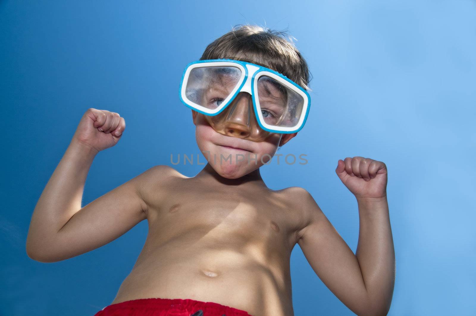 Young boy with attitude showing his muscles and wearig swiming googles