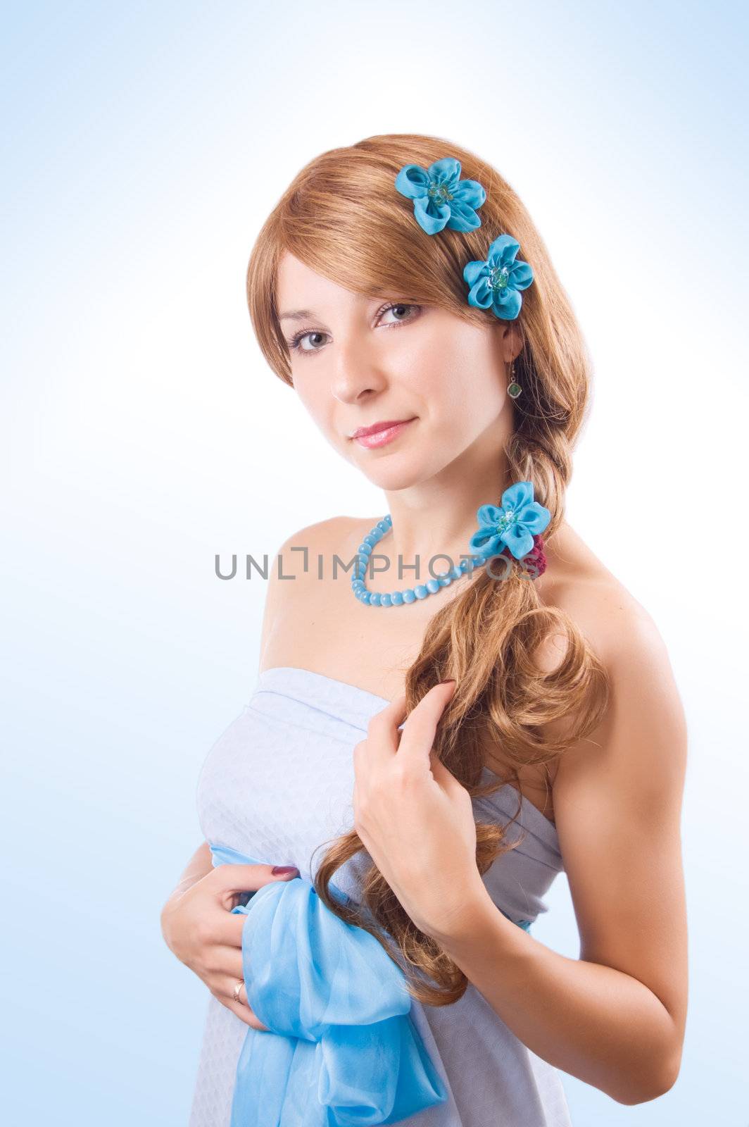 Woman in blue dress with flowers in hair over light blue back