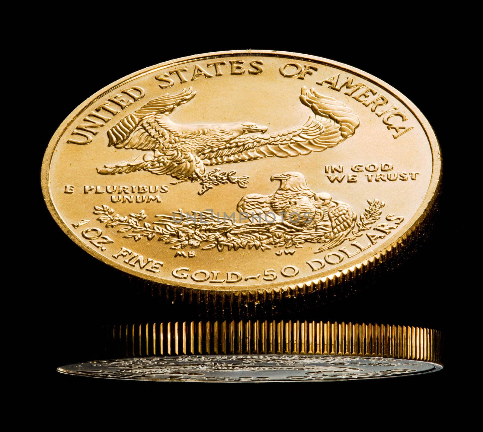 Close up of a solid gold eagle one ounce coin reflected in black shiny surface