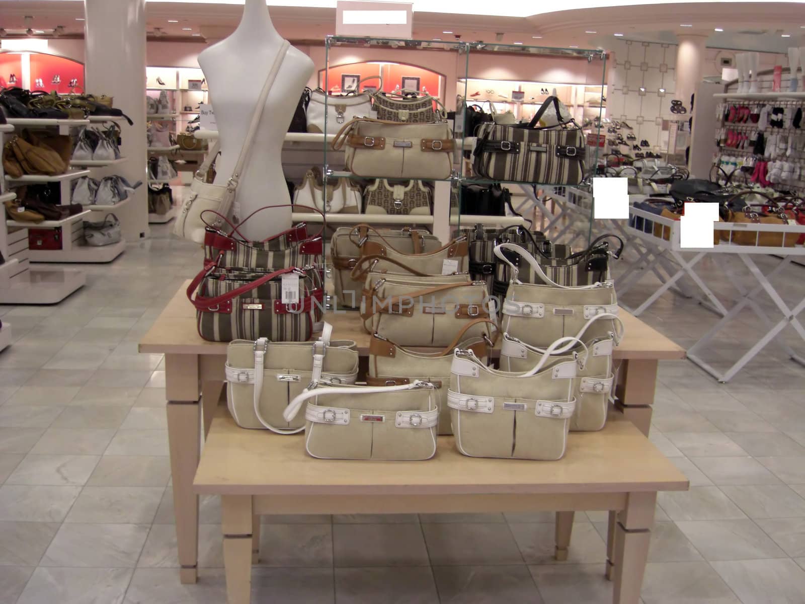 A retail department is displaying a variety of designer handbags in all colors, sizes, and shapes.