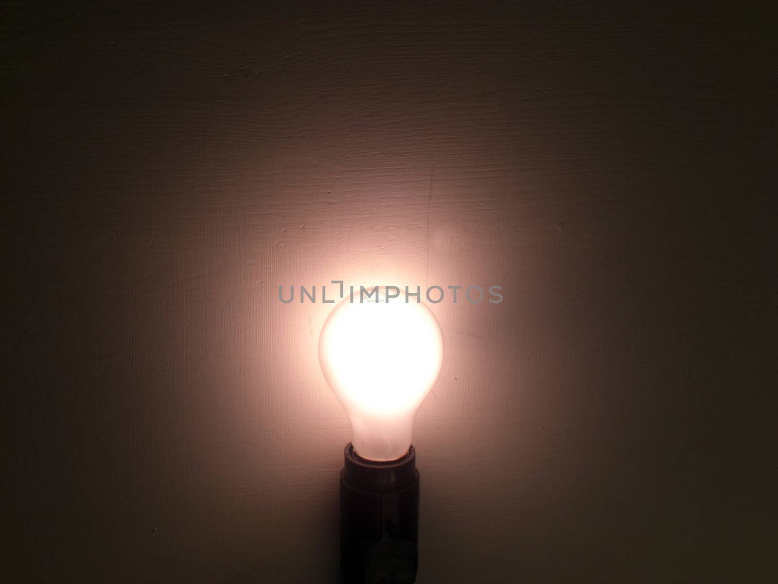 A lit bulb is surrounded by the darkness.