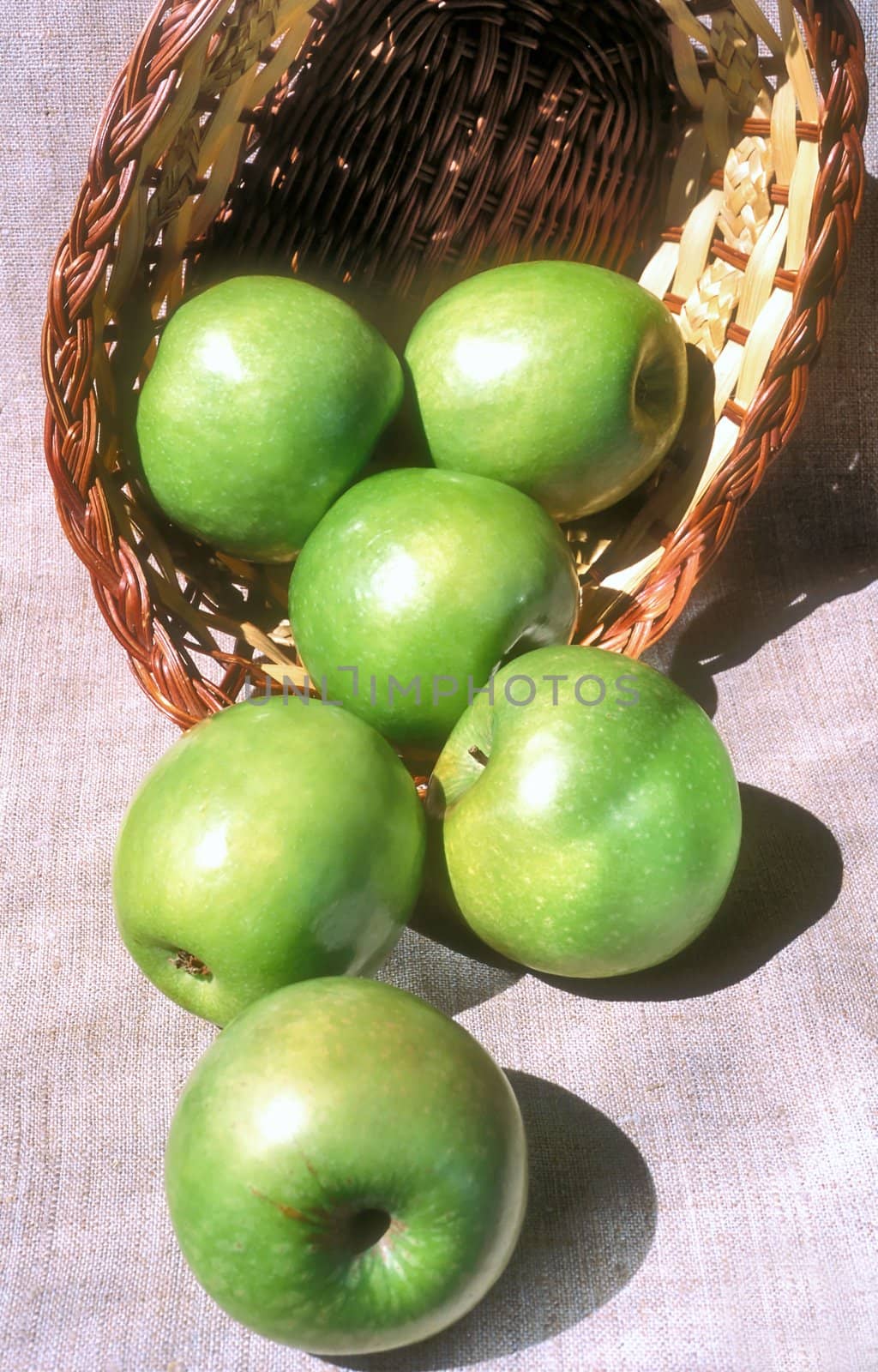 Green apples and the basket close up on canvas