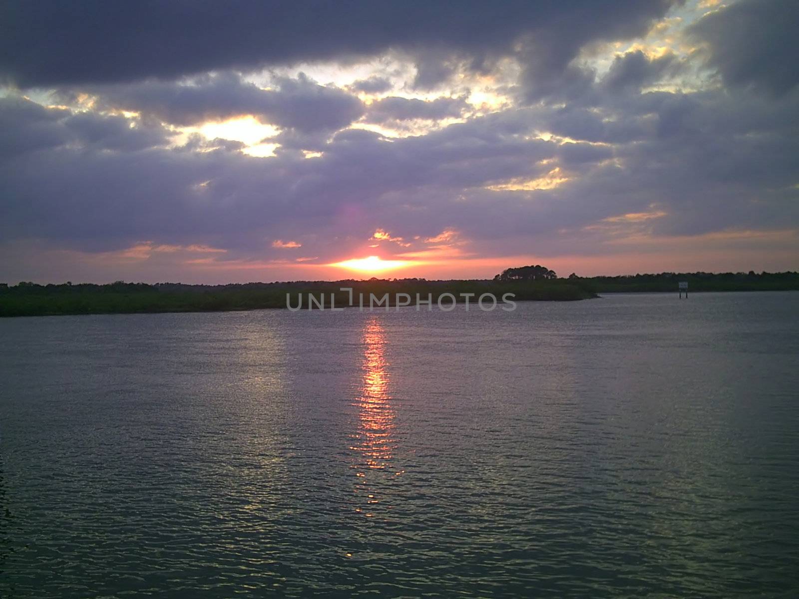 A serene reflection of the sky is sprawled in a very calm lake as the sun gradually prepares to call it a day.