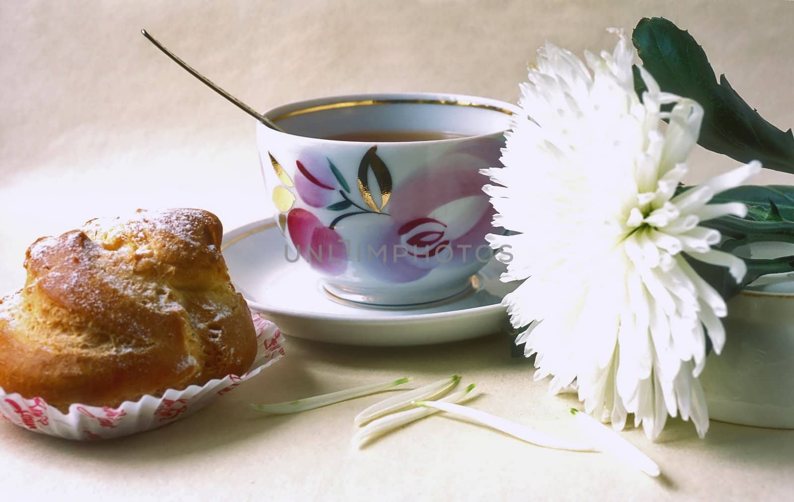 Cup of tee with cream puff and  white chrysanthemum