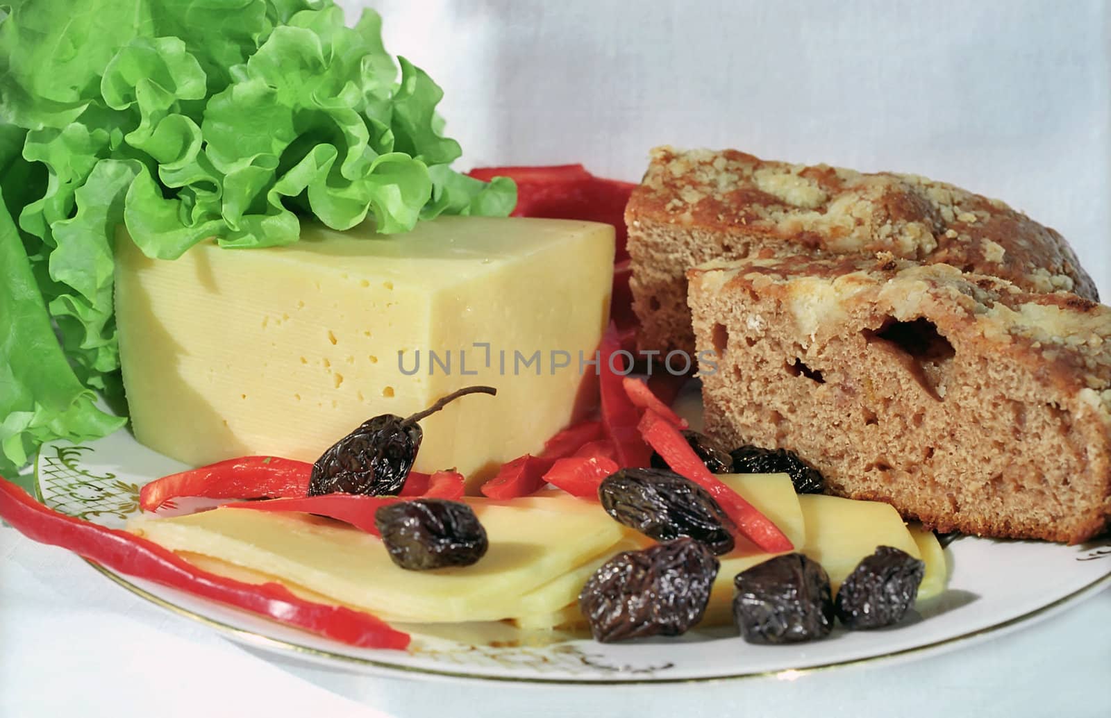 Cheese, olives, lettuce, paprica and farm bread on the plate
