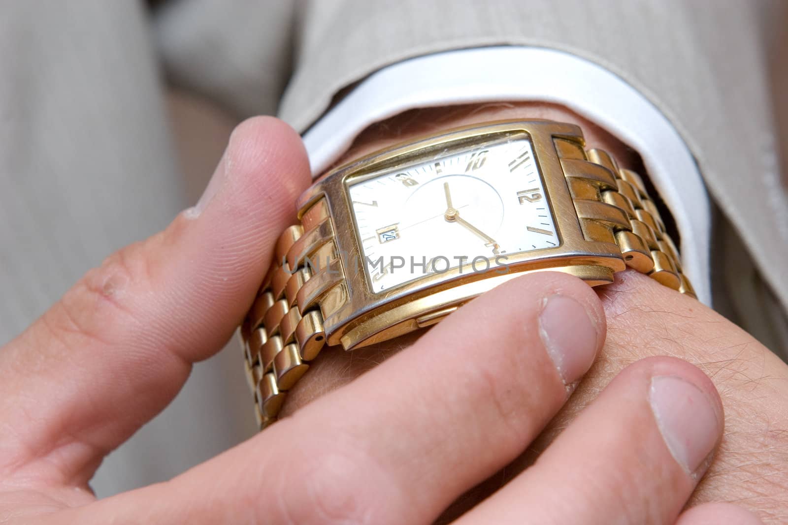 a golden watch on the hand of a man in a light suit