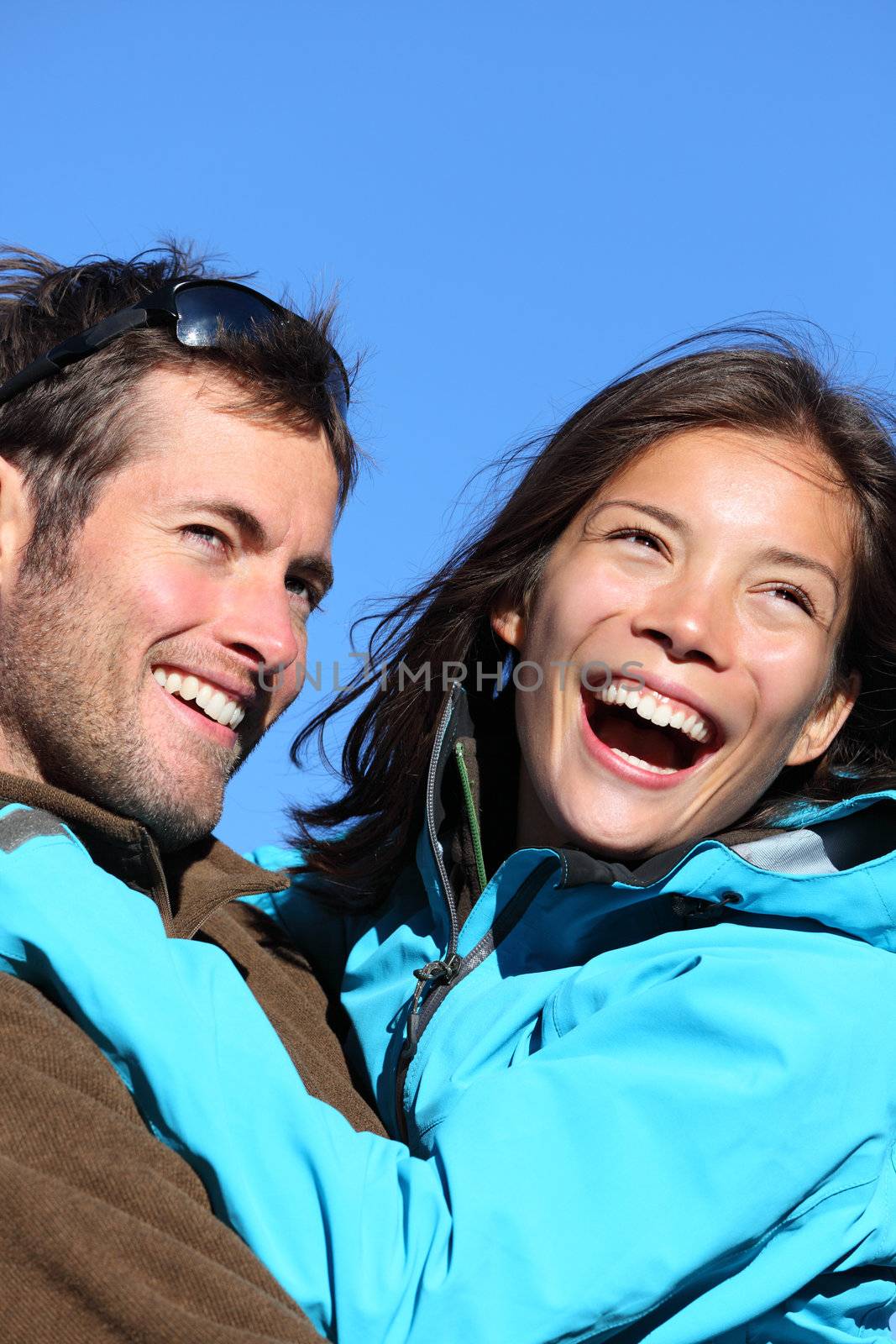 Happy young couple active outdoors. Smiling portrait of couple outside in jackets during hiking vacation. Asian woman model and Caucasian male model/