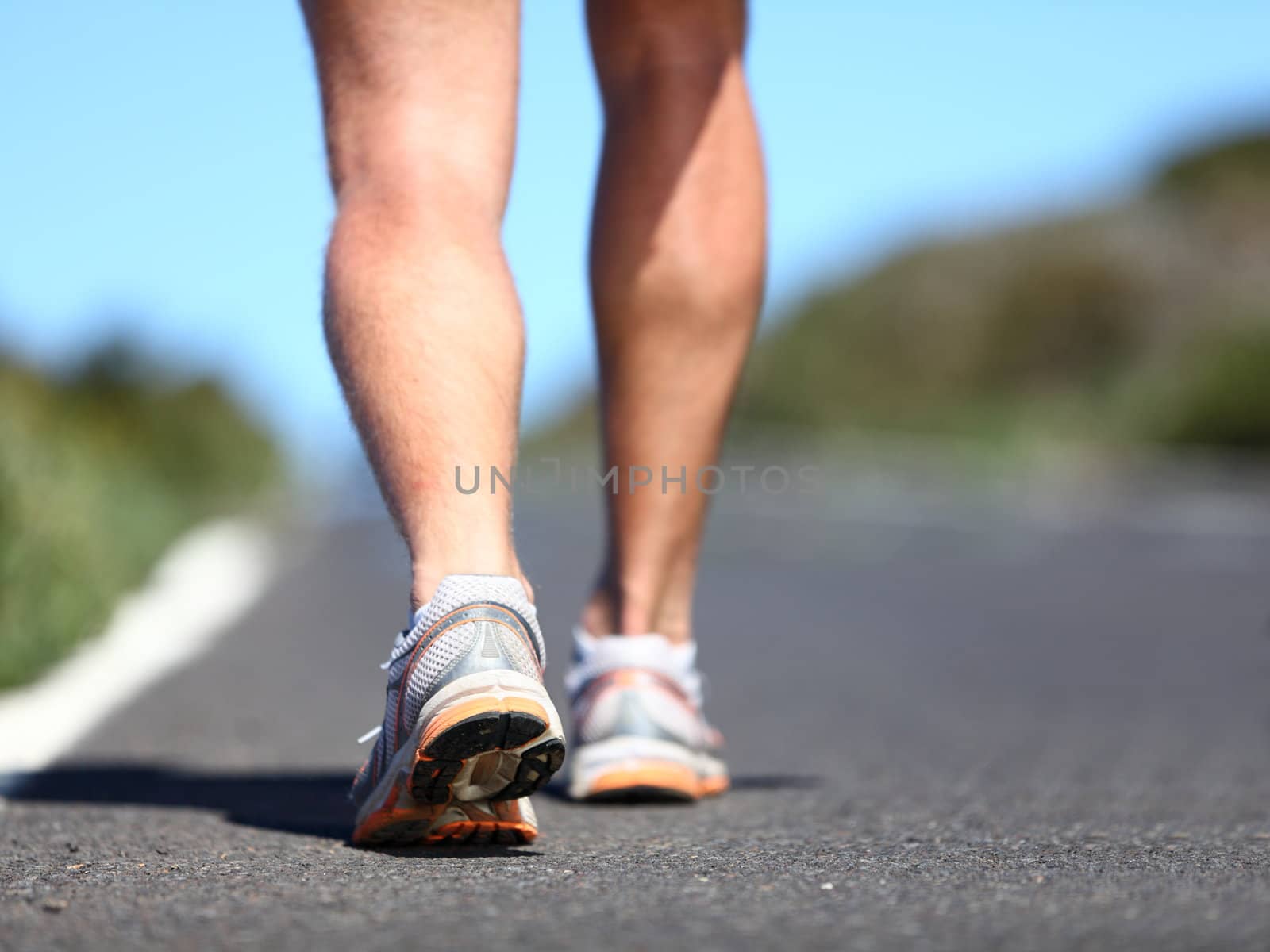 Jogging man. Running shoes and legs of male runner outside on road.