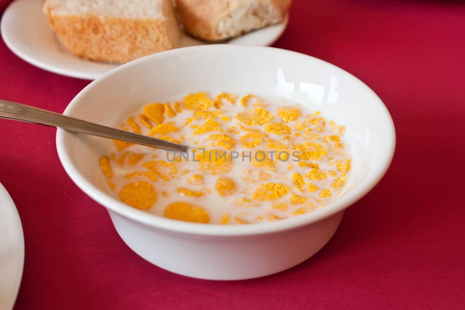 Bowl and spoon with corn flakes on the table by aleksan