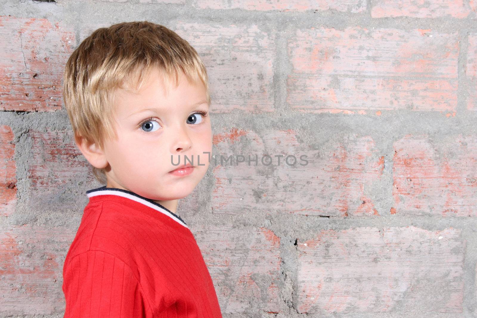 Cute toddler boy against a brick wall background