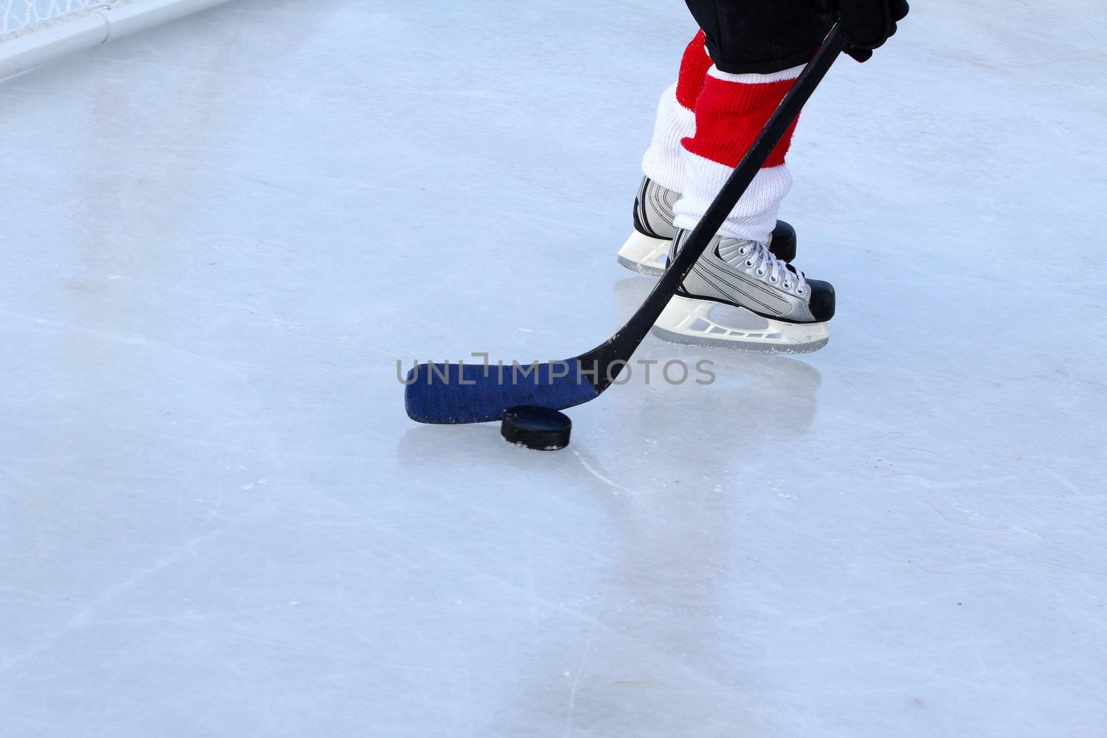 Young child playing ice hockey on a pond