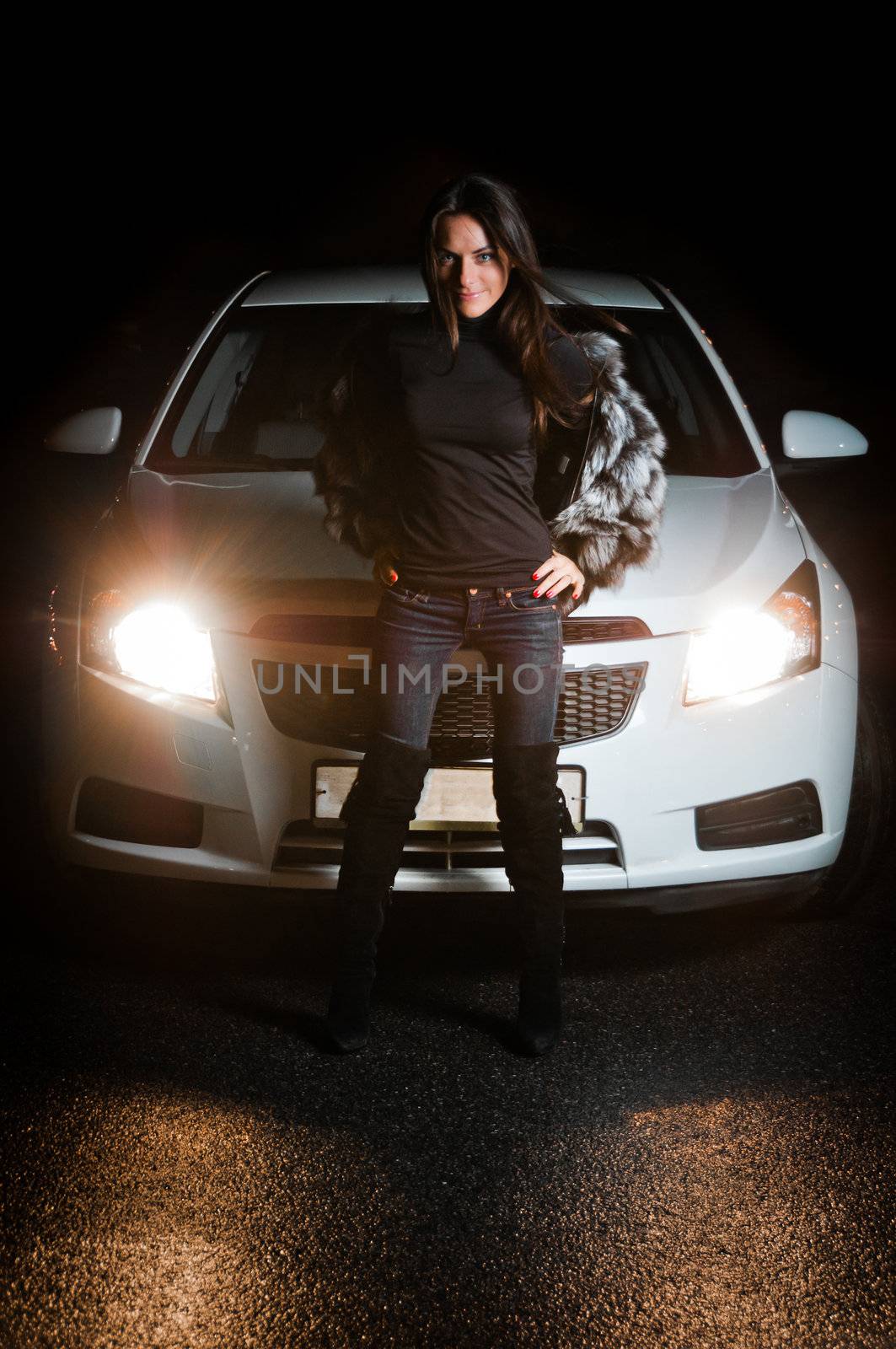 Pretty girl in front of car with enabled headlights