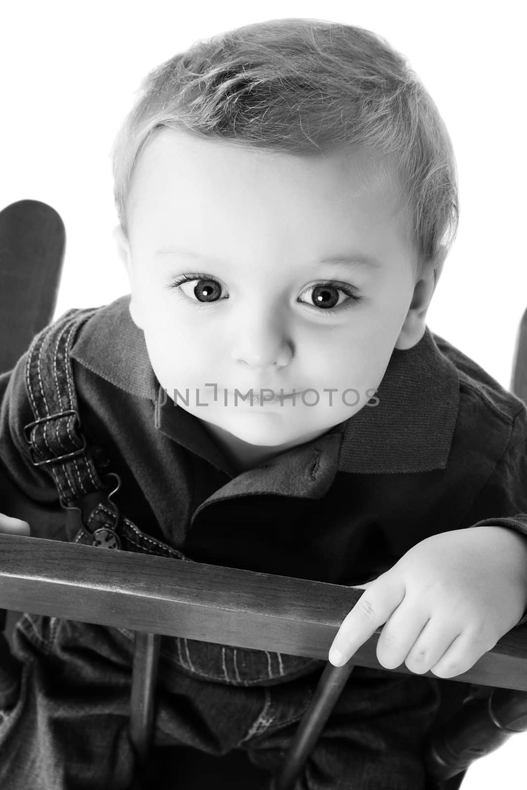 Cute baby boy sitting on a chair looking up