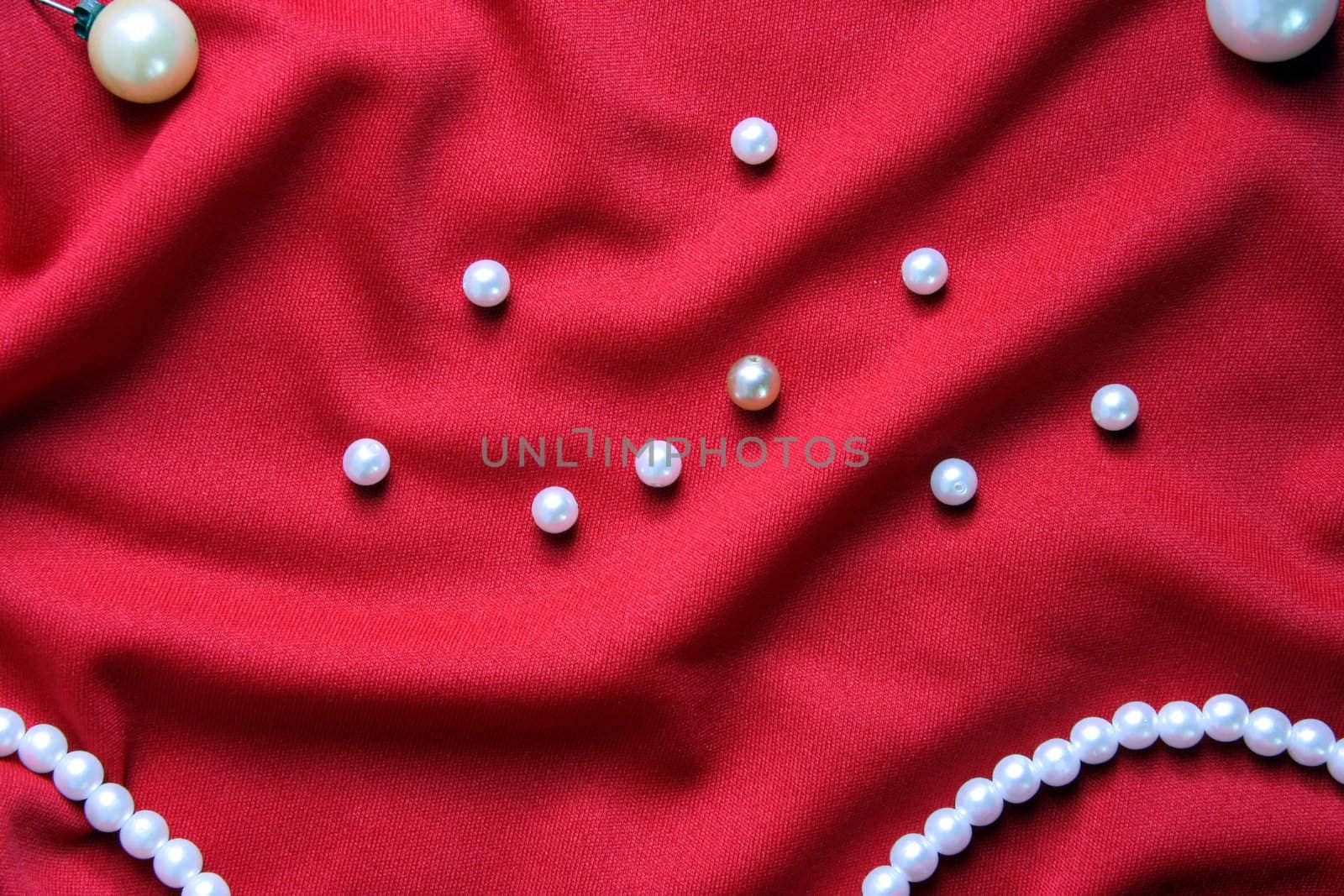 Nacreous pearls and necklace on a red fabric with folds