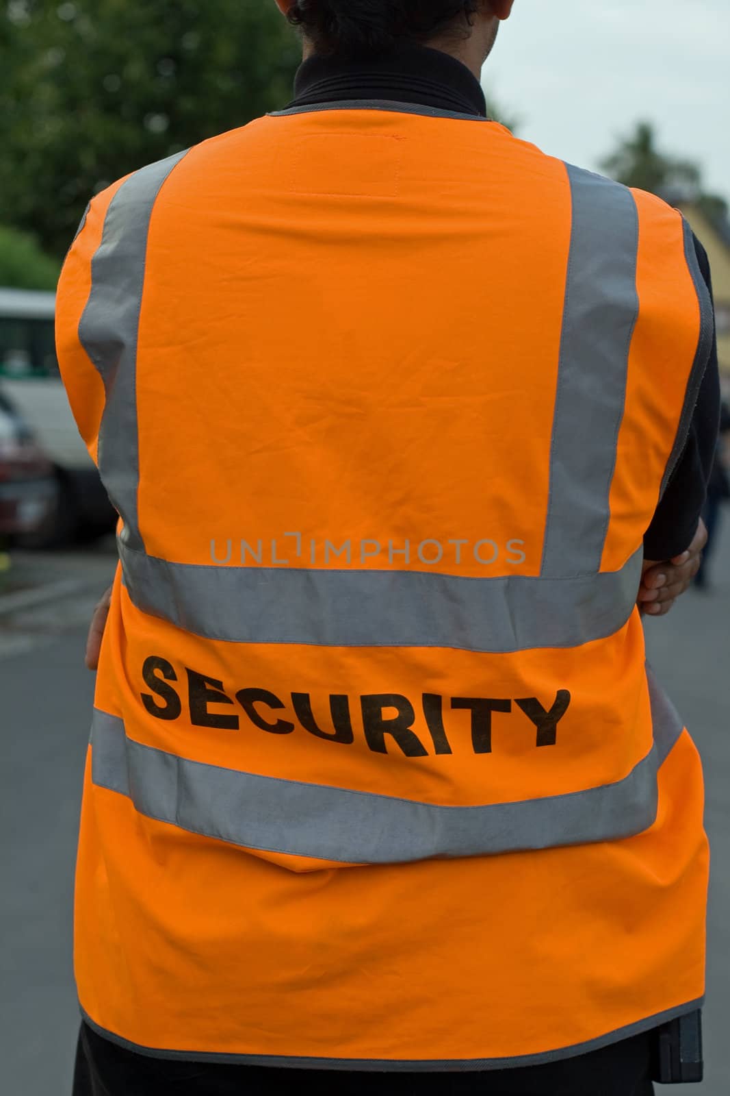 Back of a security guard in orange uniform jacket